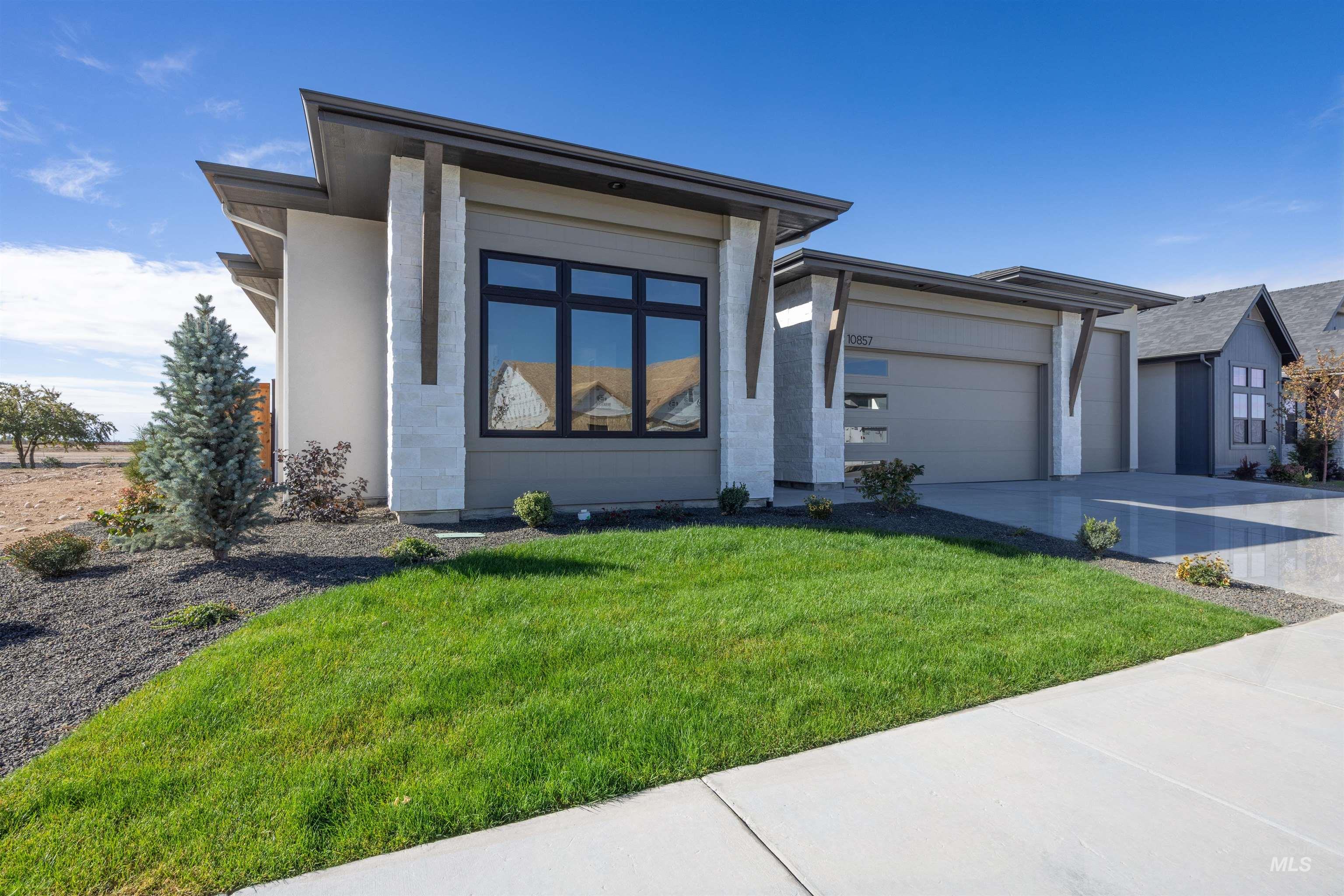 Prairie-style home with driveway, a garage, stucco siding, and a front lawn