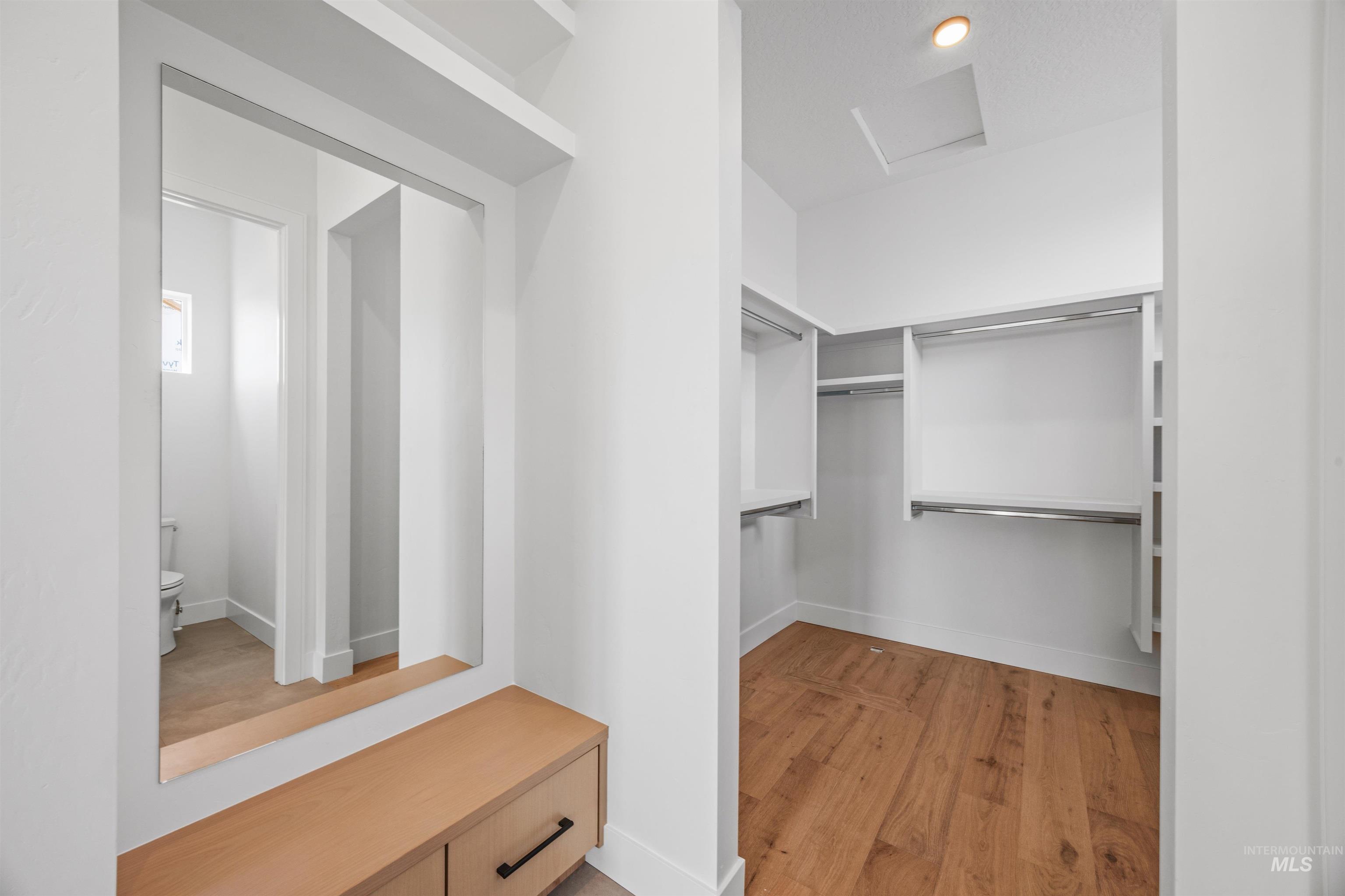 Walk in closet featuring attic access and light wood-style floors