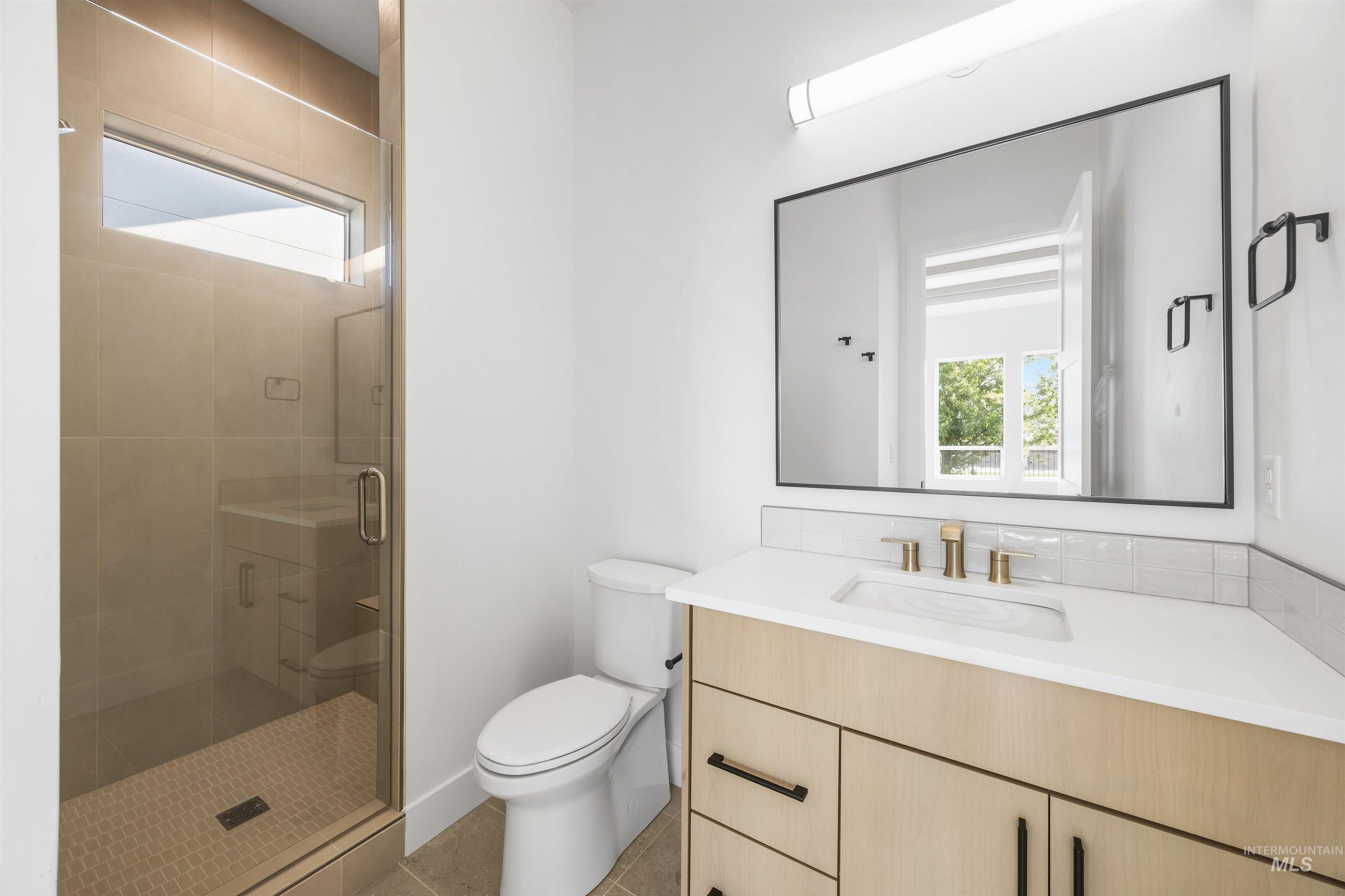 Bathroom featuring plenty of natural light, vanity, a stall shower, and light tile patterned flooring
