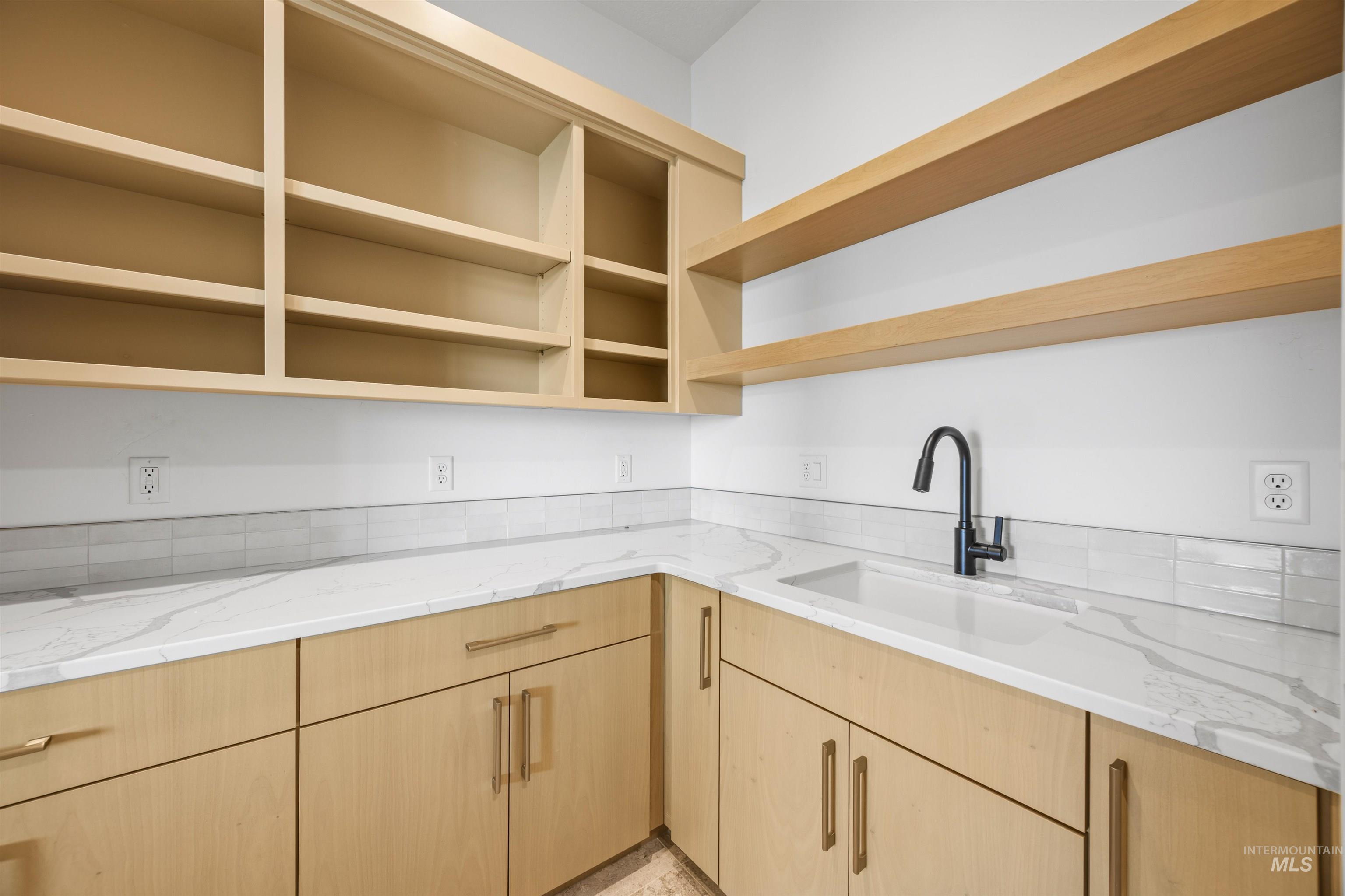 Laundry featuring light brown cabinetry and light stone counters