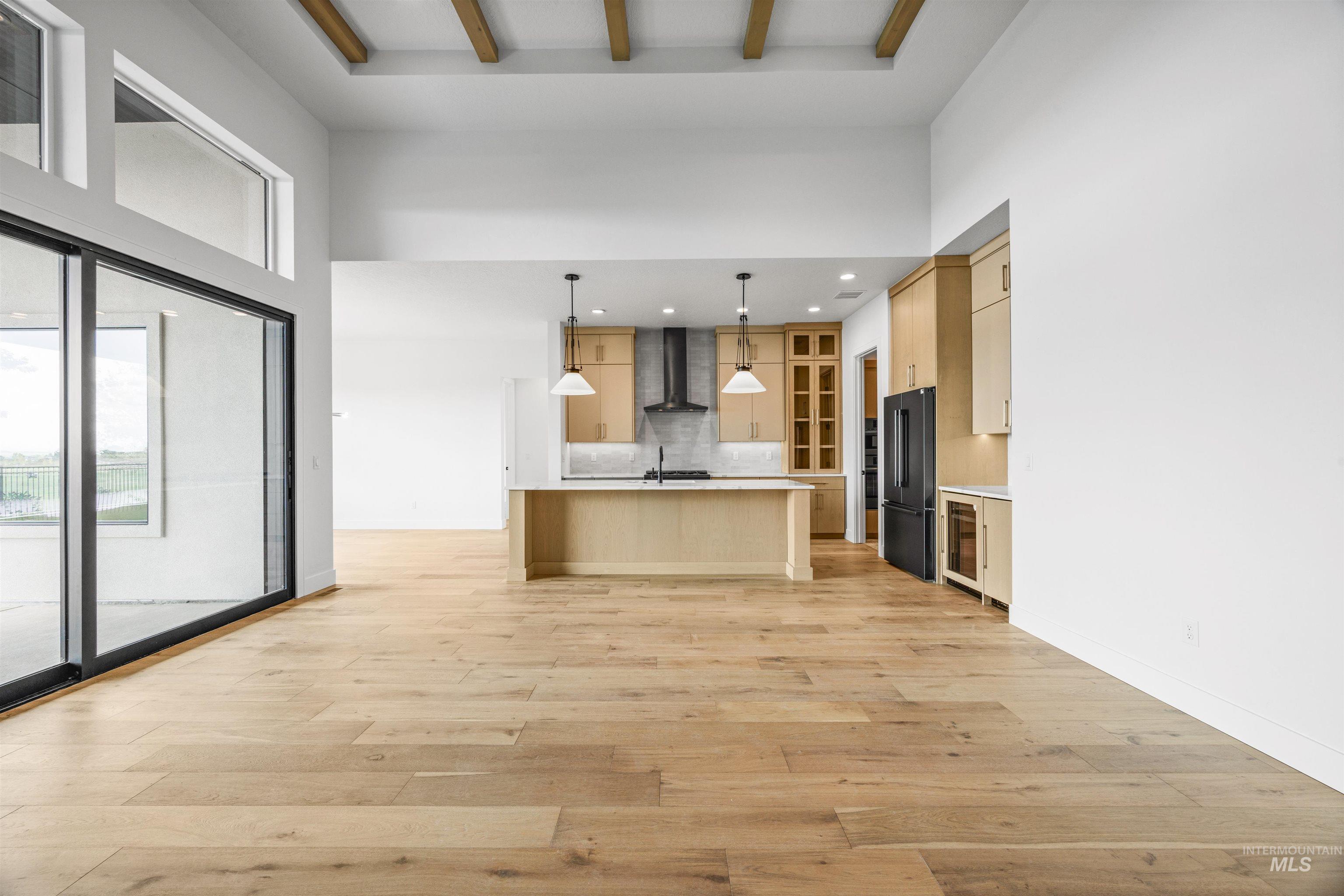 Kitchen featuring light brown cabinetry, decorative light fixtures, light countertops, light wood finished floors, and backsplash