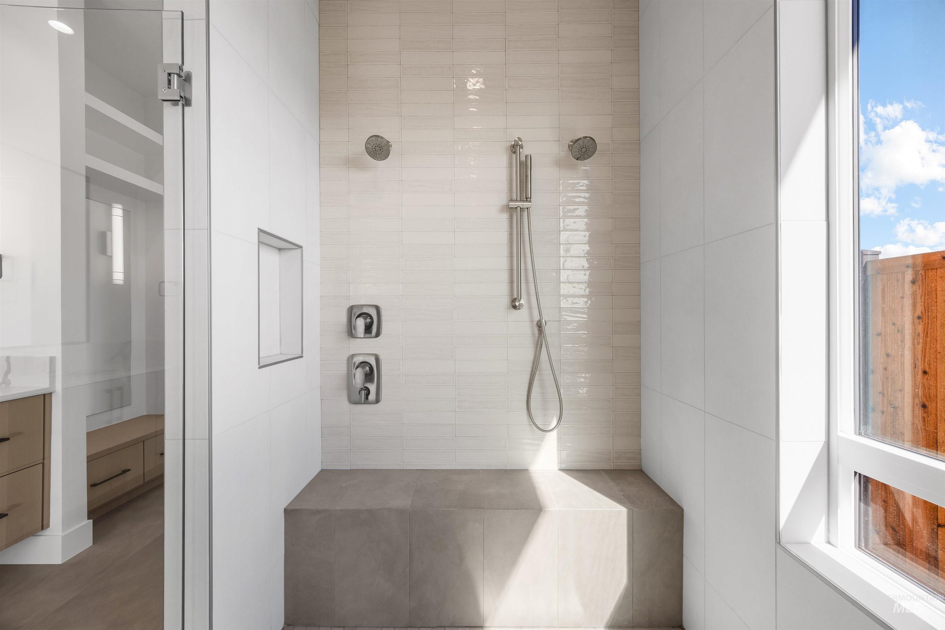 Full bath with vanity, a tile shower, and tile walls