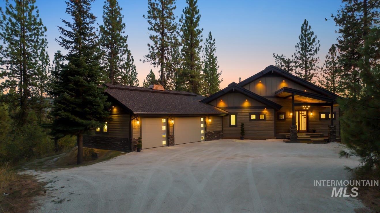 View of front of home featuring driveway, a garage, stone siding, a chimney, and a shingled roof