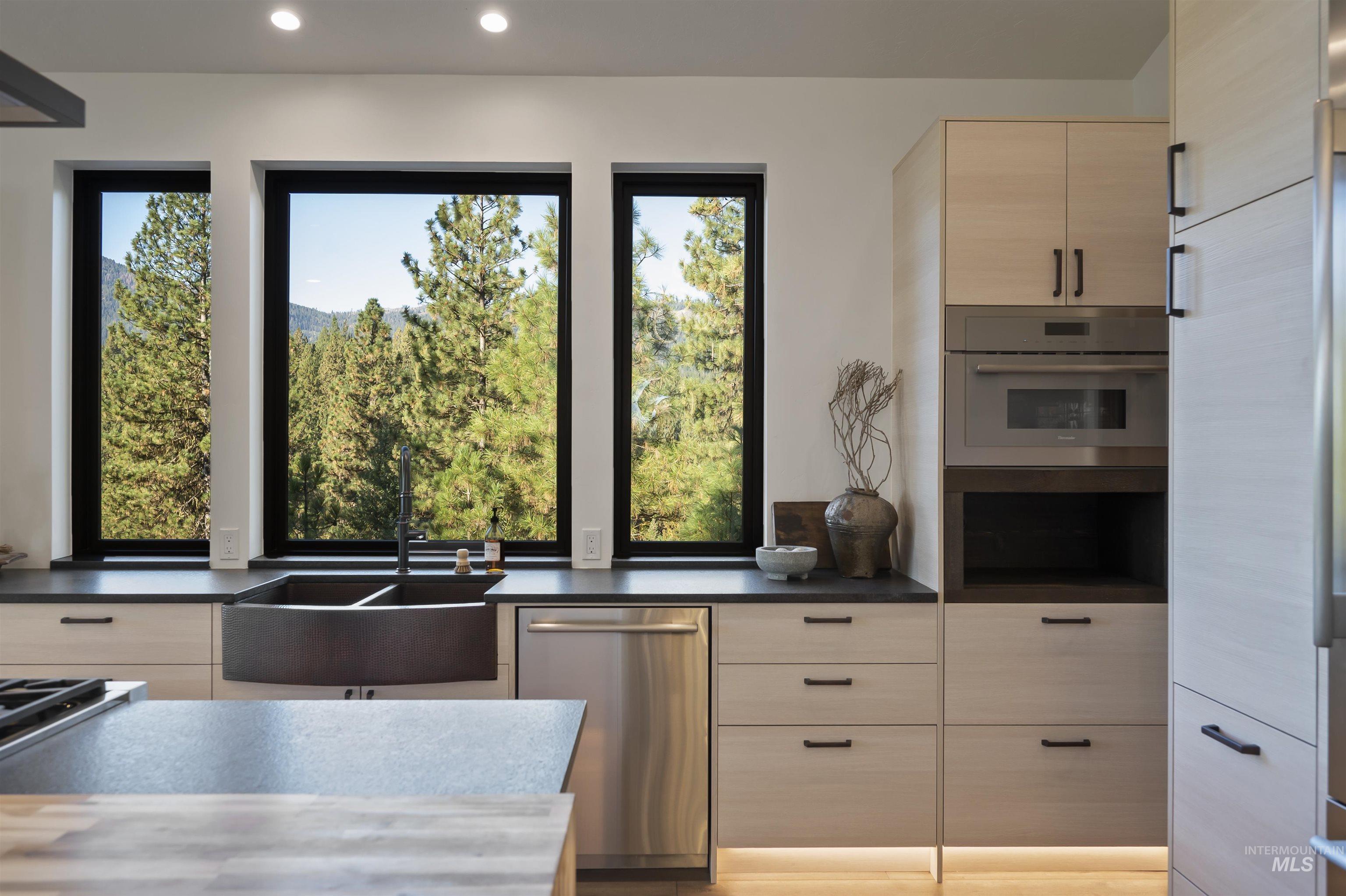 Kitchen featuring stainless steel appliances, plenty of natural light, modern cabinets, light brown cabinets, and recessed lighting