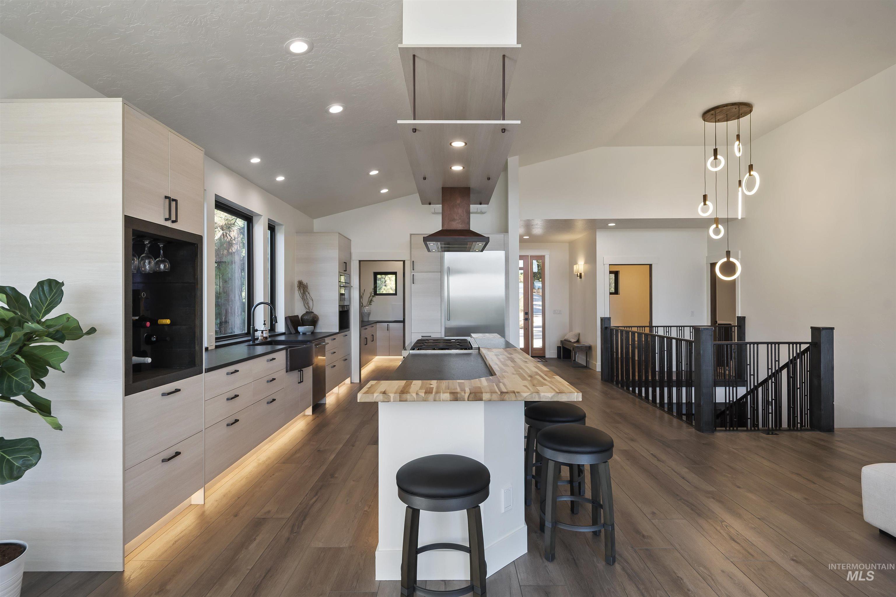 Kitchen featuring vaulted ceiling, modern cabinets, wooden counters, a center island, and a breakfast bar area