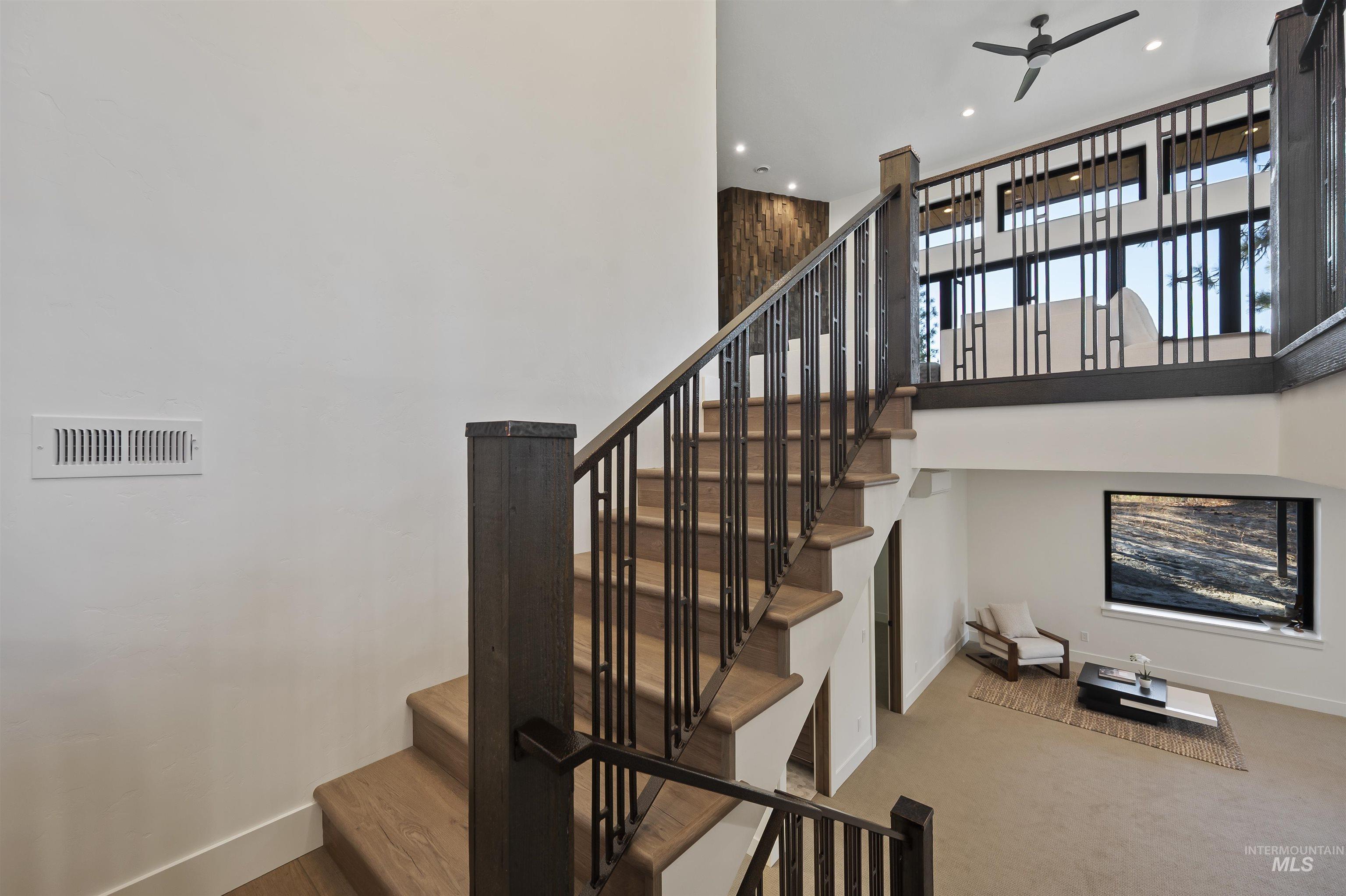 Staircase featuring a towering ceiling, a ceiling fan, and recessed lighting