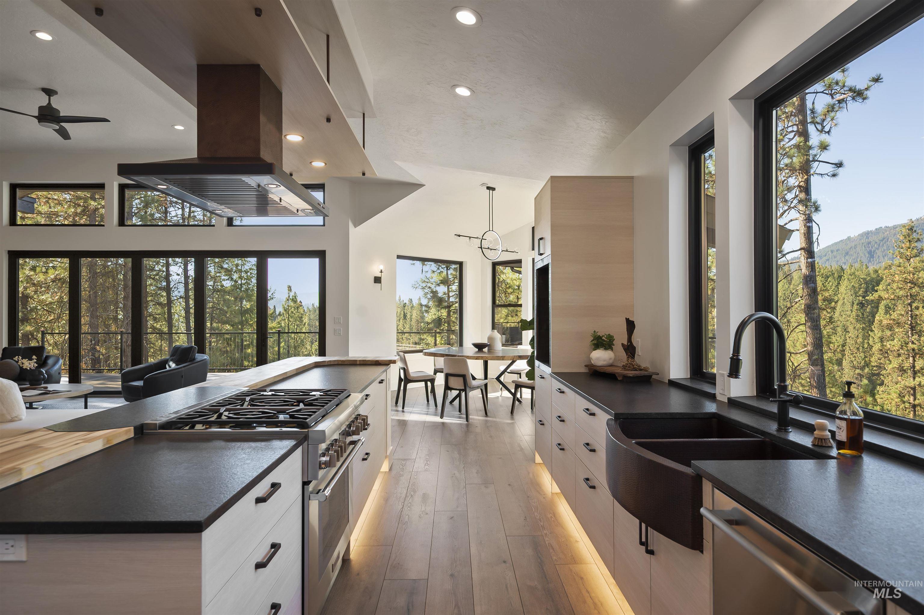 Kitchen with dark countertops, stainless steel appliances, recessed lighting, hardwood / wood-style flooring, and island range hood