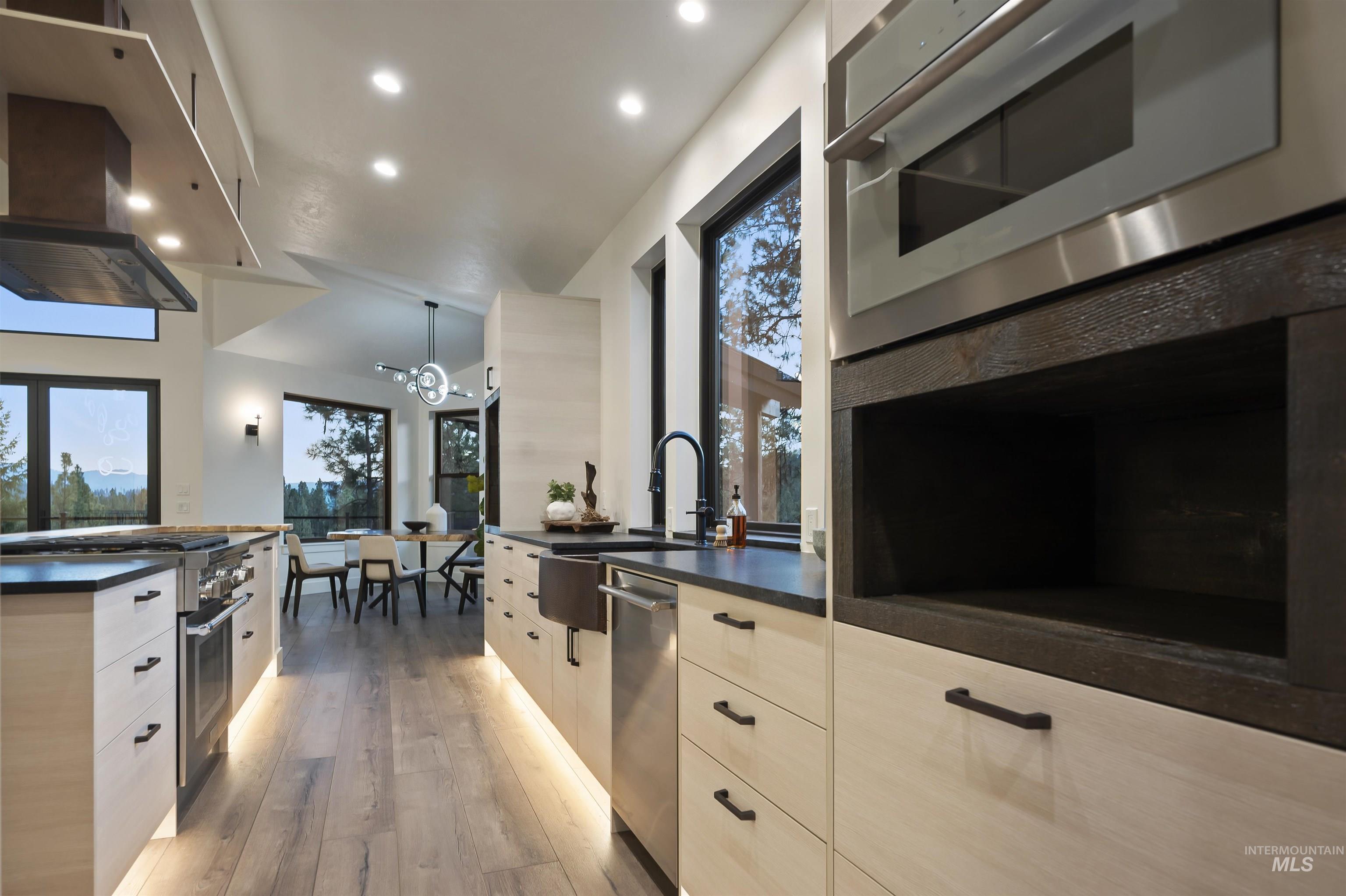 Kitchen featuring modern cabinets, dark countertops, appliances with stainless steel finishes, a chandelier, and recessed lighting