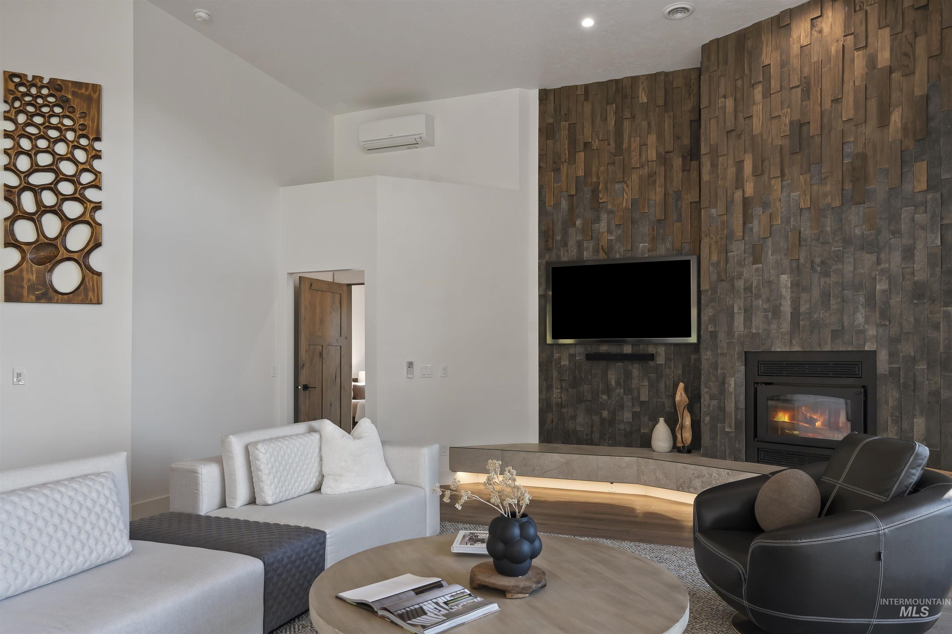 Living area featuring a high end fireplace, a high ceiling, and a wall mounted AC