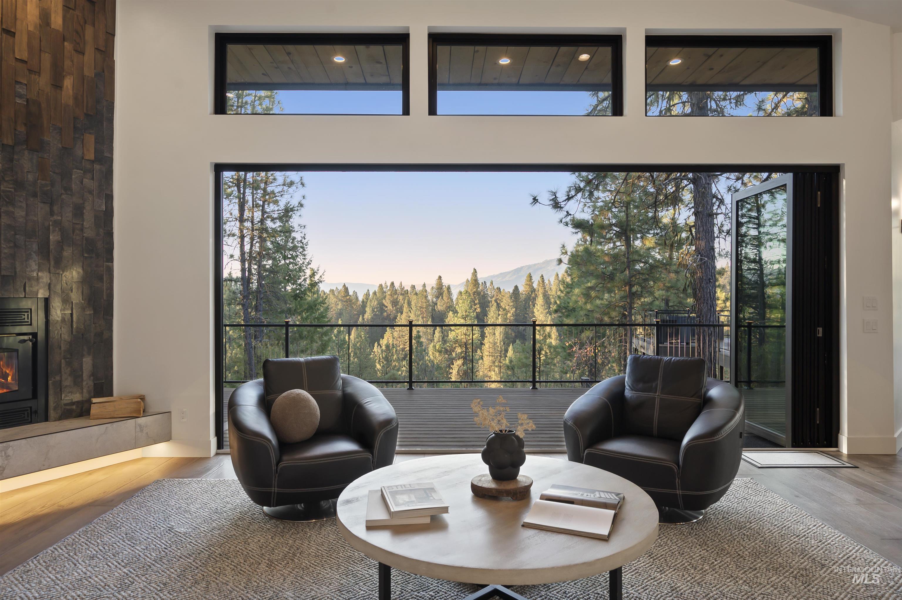 Sitting room with wood finished floors, a towering ceiling, a glass covered fireplace, and a mountain view