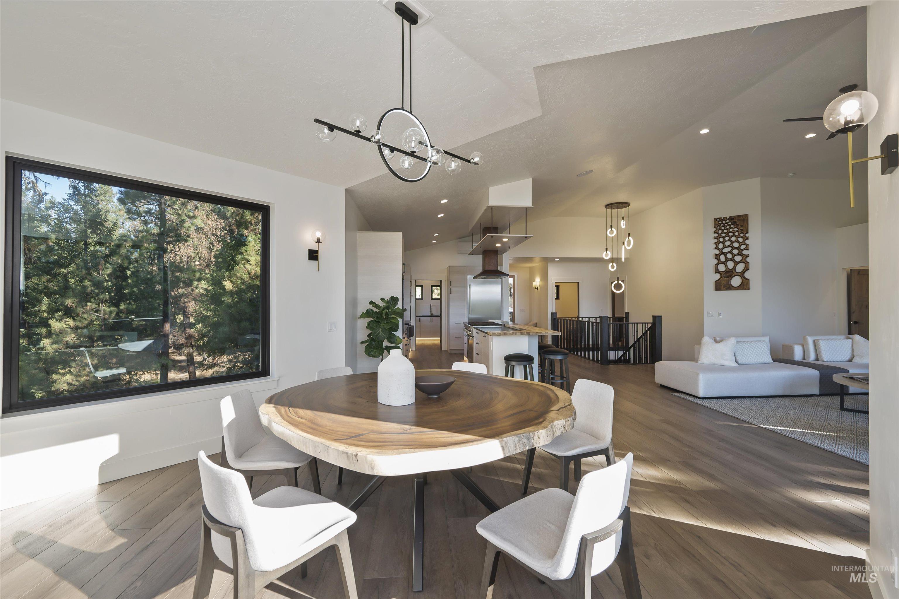 Dining room featuring wood finished floors, a chandelier, vaulted ceiling, and recessed lighting