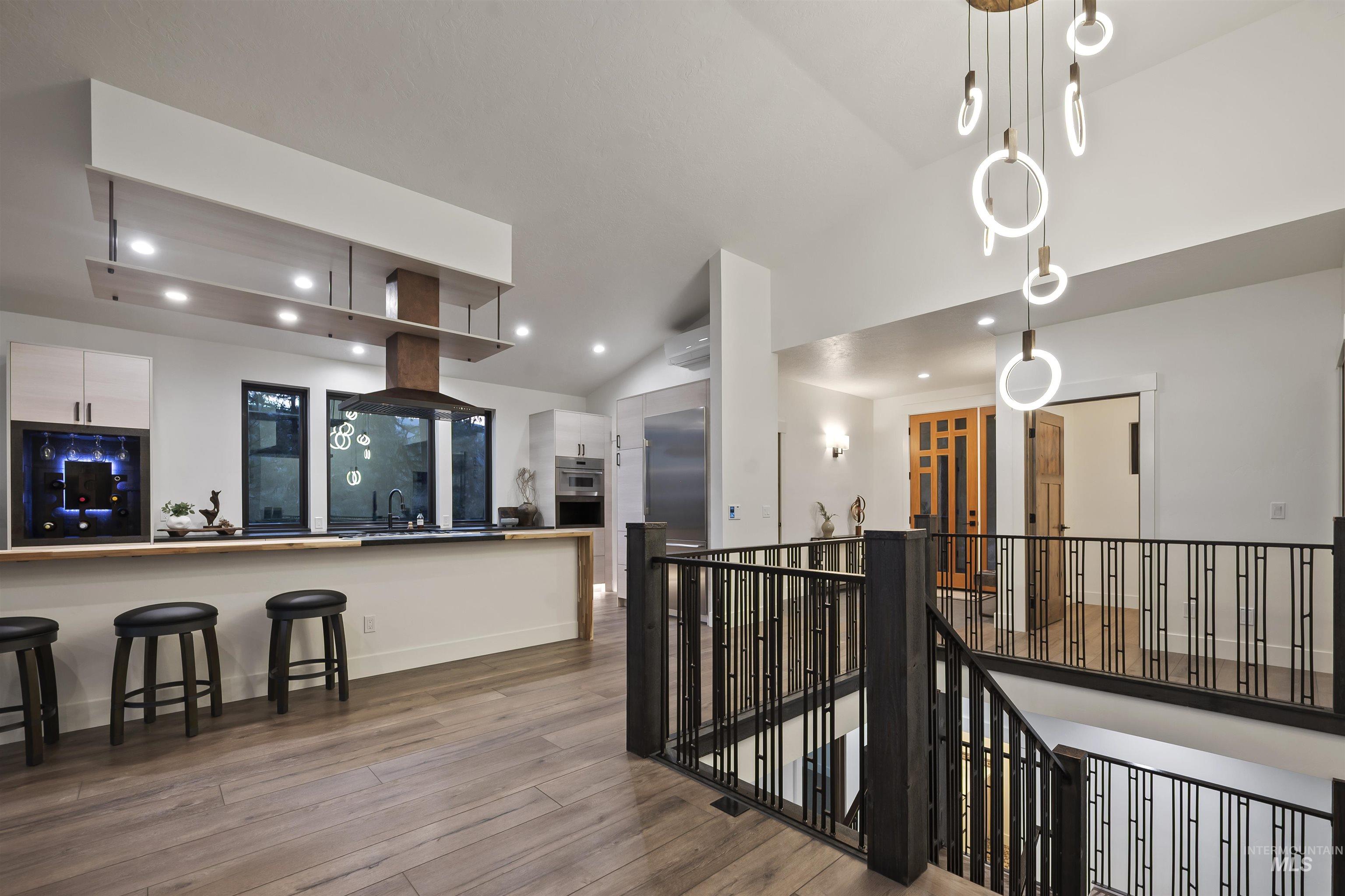 Kitchen featuring vaulted ceiling, wood finished floors, white cabinetry, recessed lighting, and appliances with stainless steel finishes