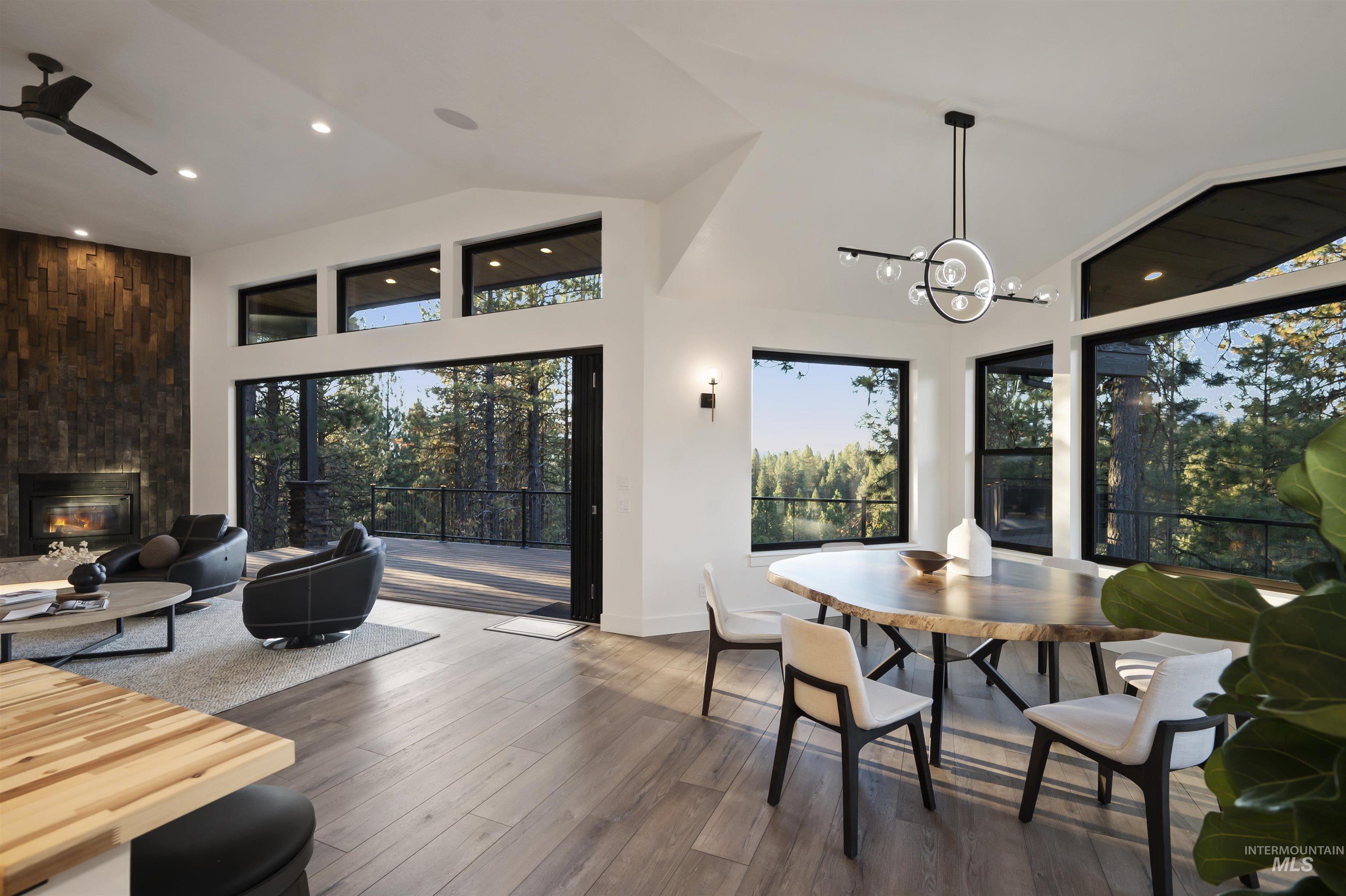 Dining room featuring a large fireplace, wood finished floors, a chandelier, a ceiling fan, and recessed lighting