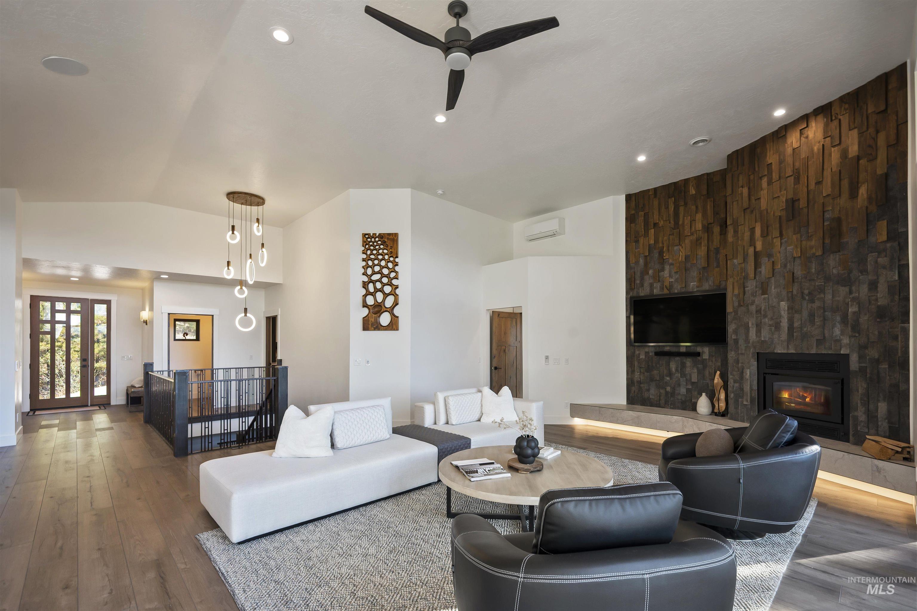 Living room featuring wood-type flooring, a fireplace, ceiling fan, vaulted ceiling, and recessed lighting
