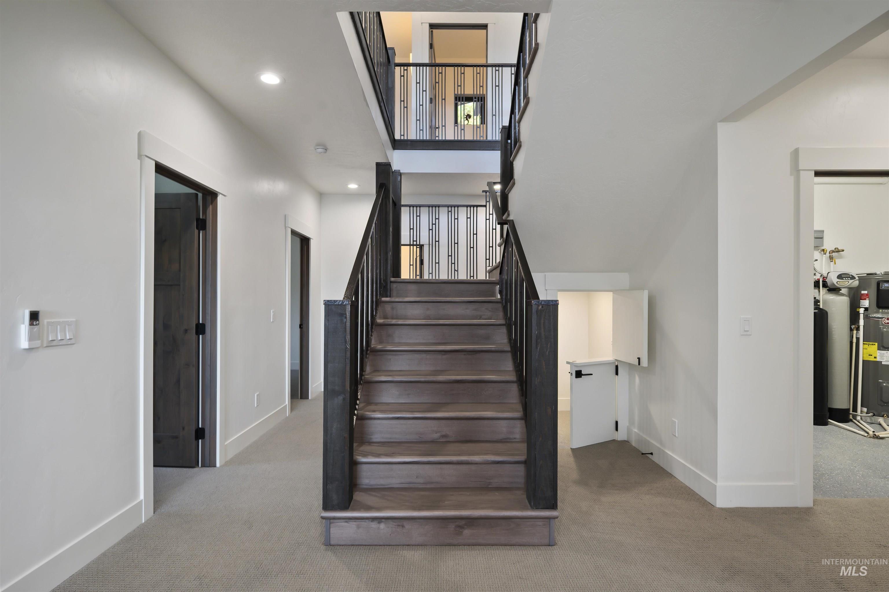 Staircase featuring carpet floors, recessed lighting, and electric water heater