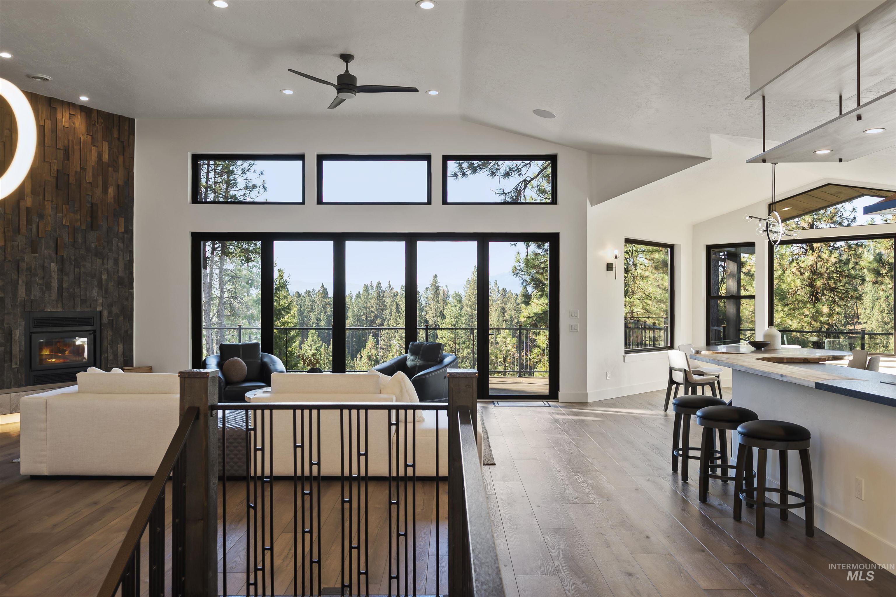 Living area with dark wood-type flooring, recessed lighting, a ceiling fan, a premium fireplace, and high vaulted ceiling