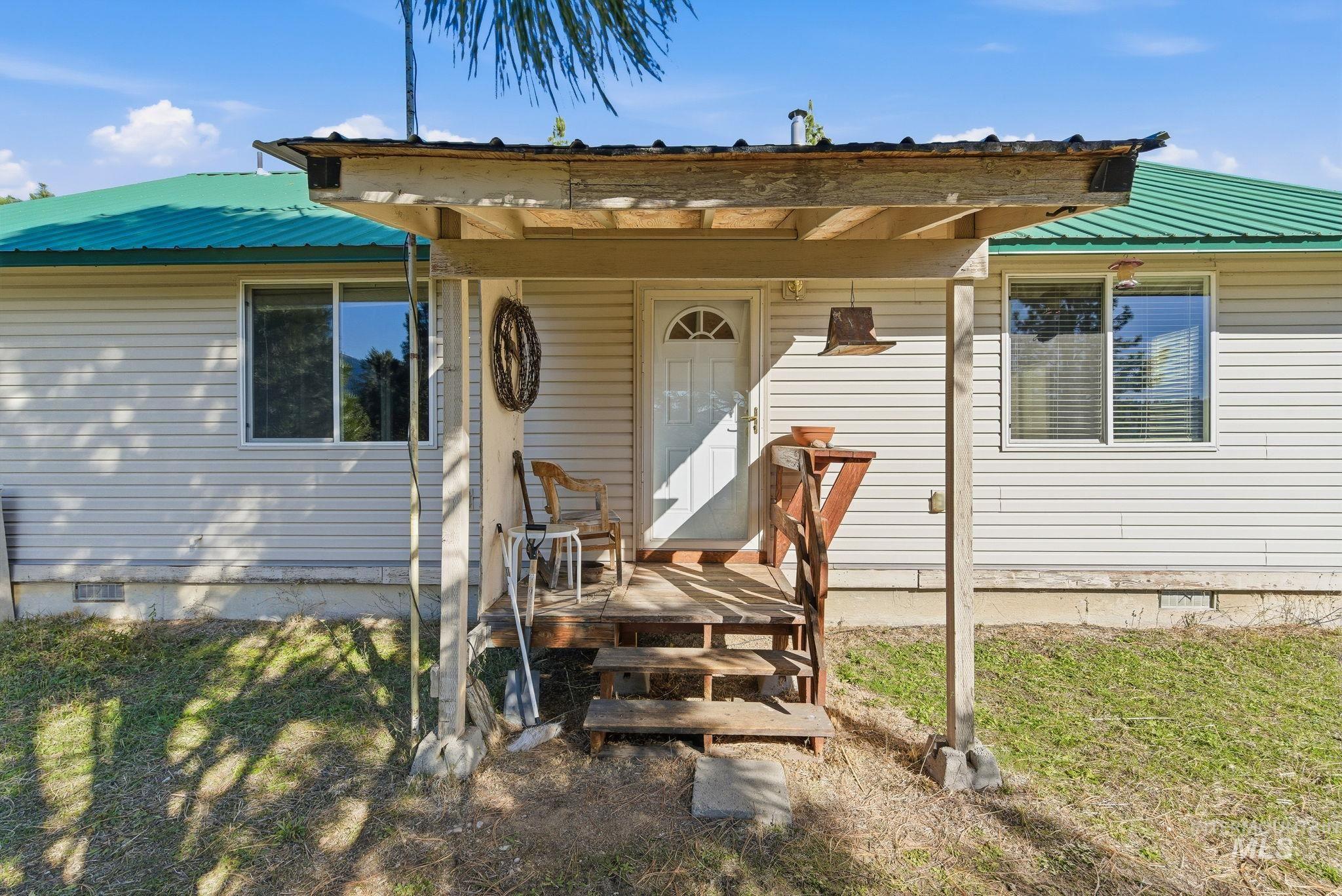 Entrance to property with crawl space, a metal roof, and a yard