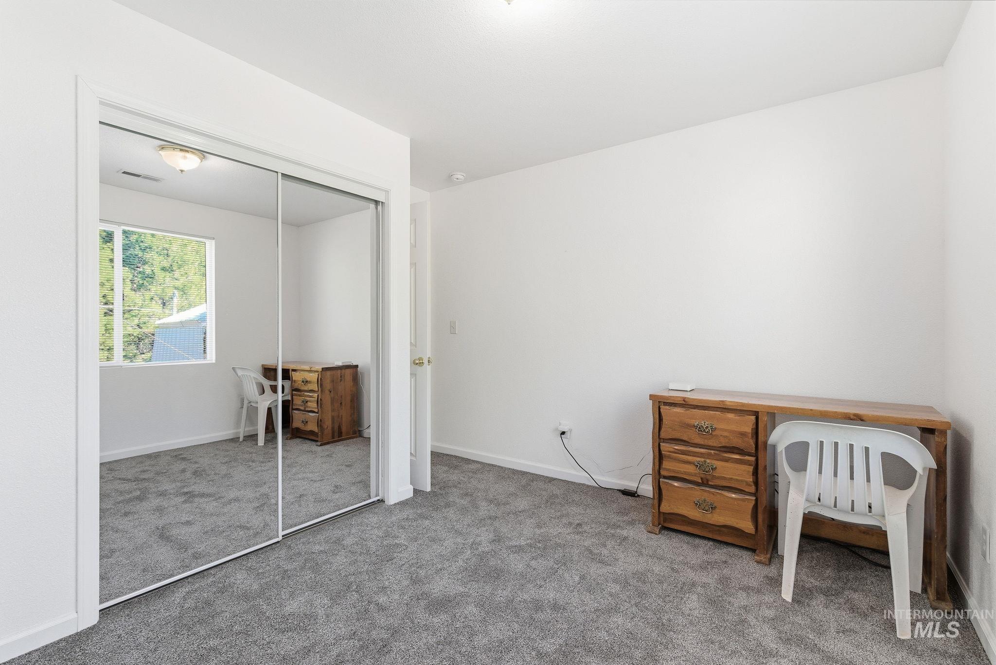 Carpeted bedroom with a closet and baseboards