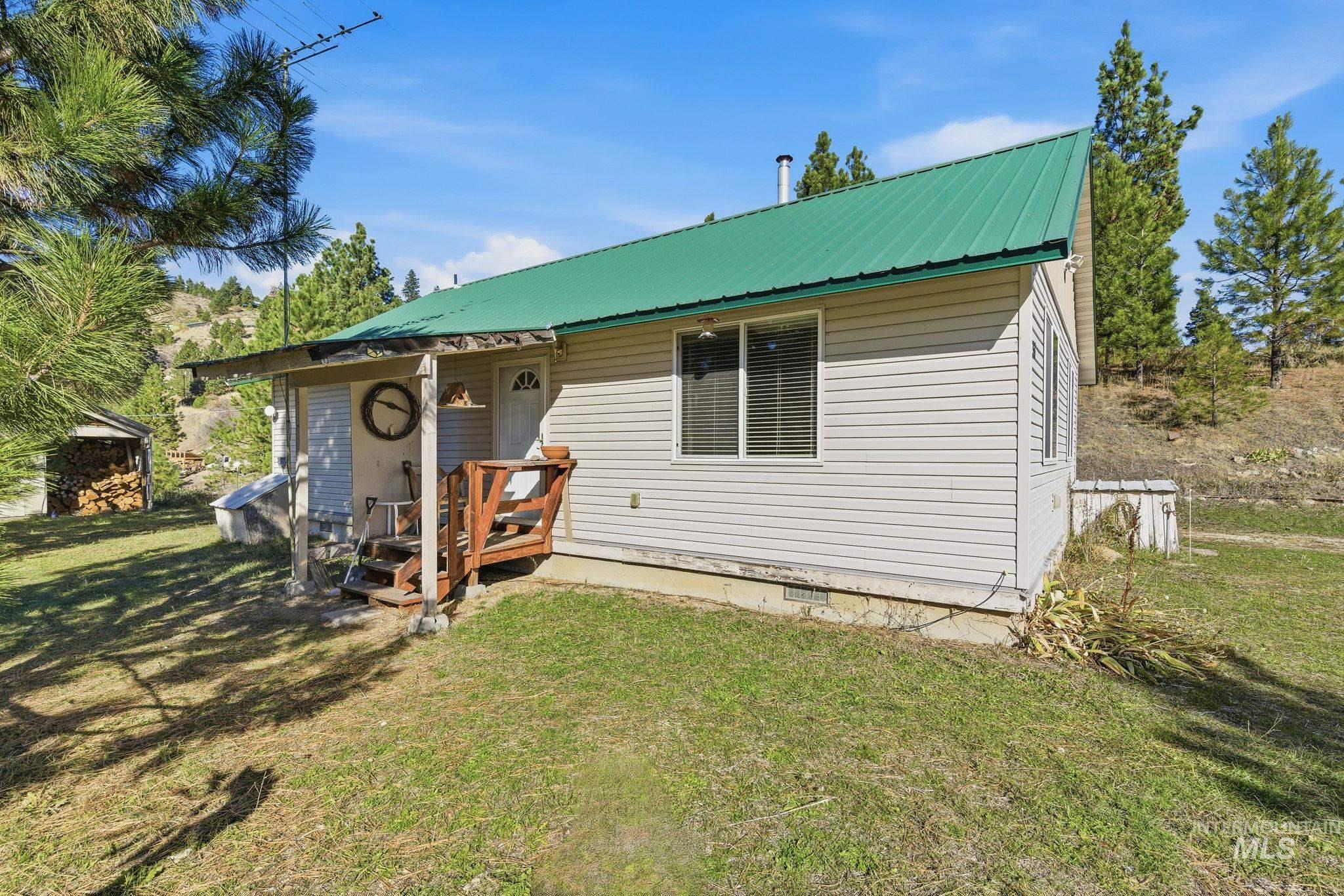 View of front of property featuring a front lawn, a deck, and a metal roof