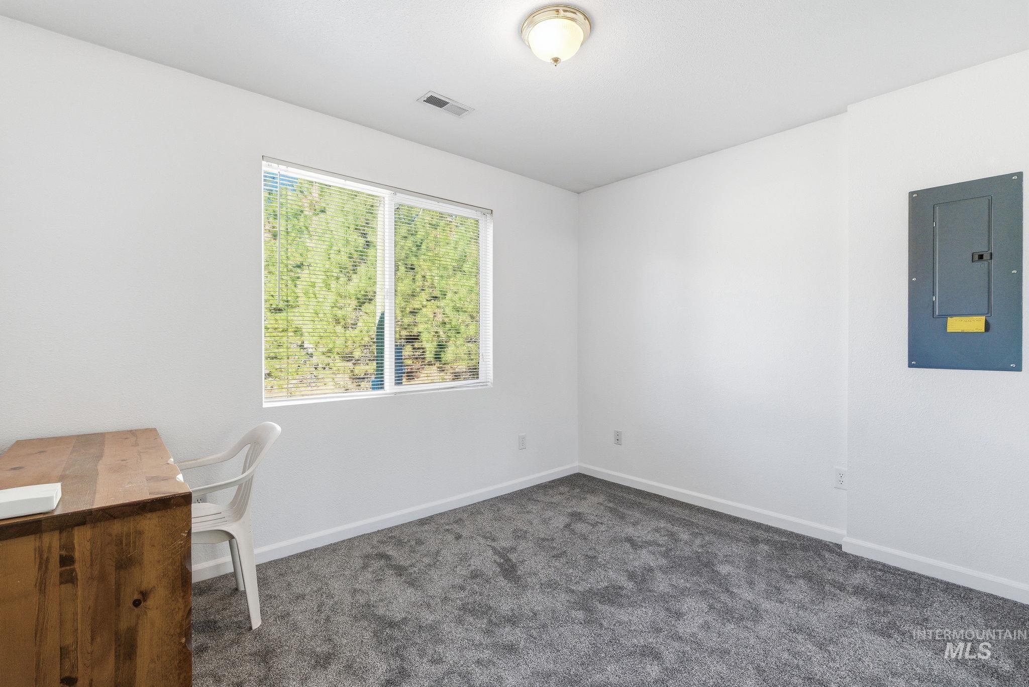 Unfurnished office featuring electric panel and dark colored carpet
