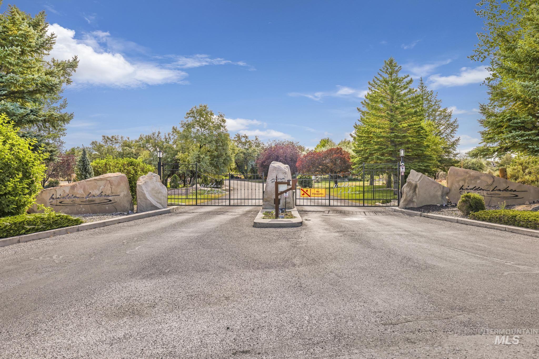 View of asphalt street with a gate, a gated entry, and curbs