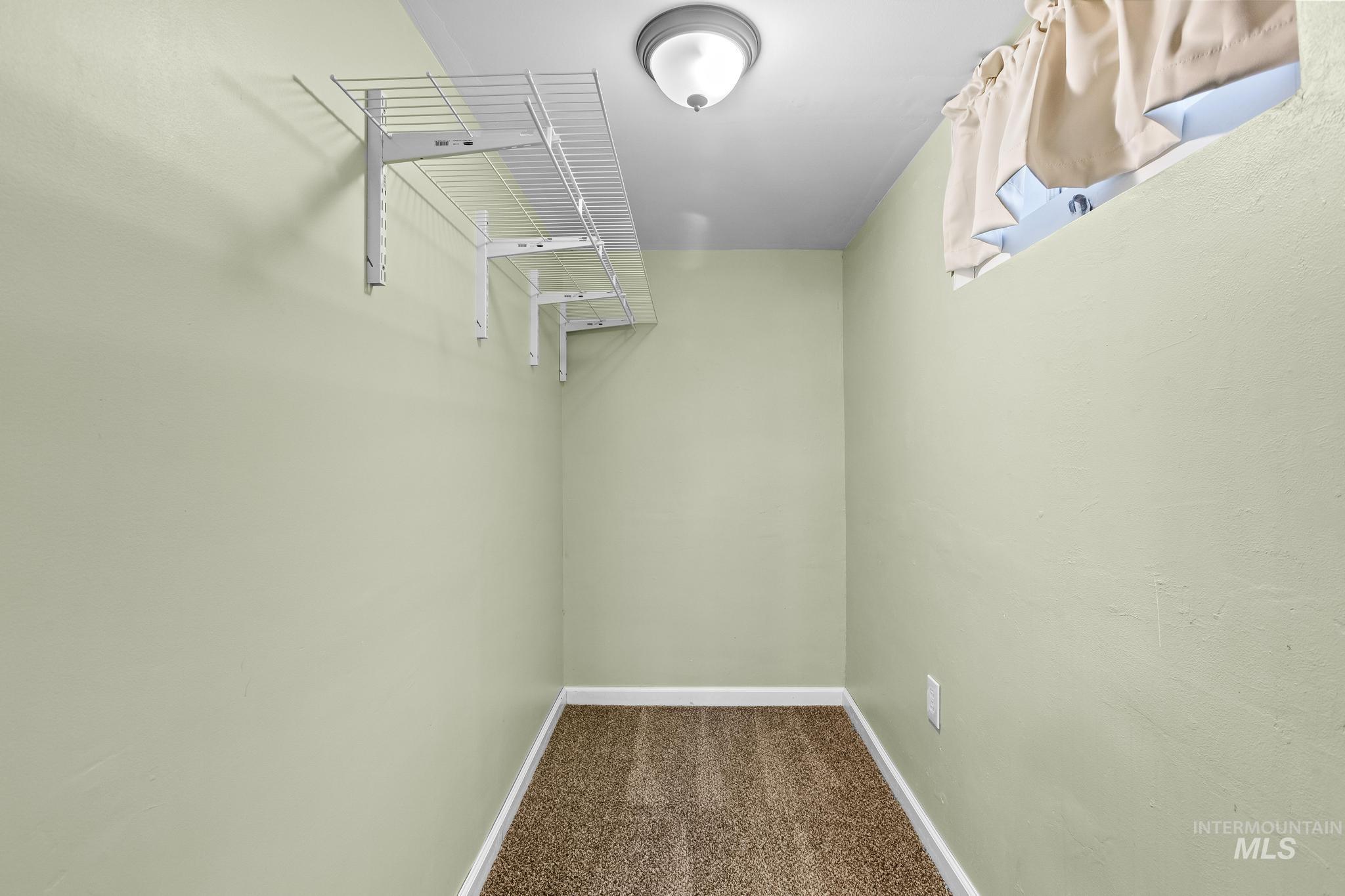 Walk in closet featuring dark colored carpet