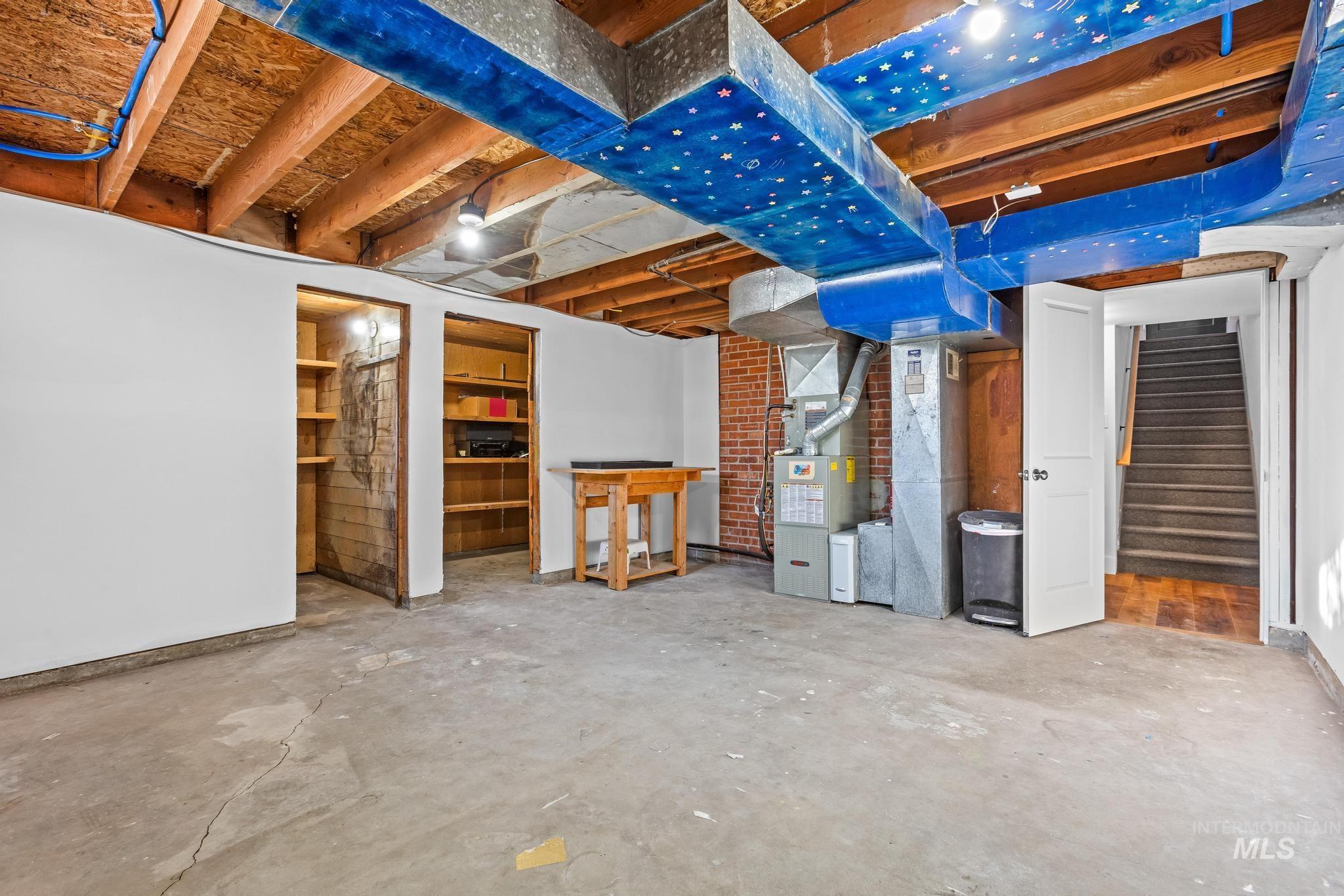 Unfinished below grade area featuring heating unit and stairs