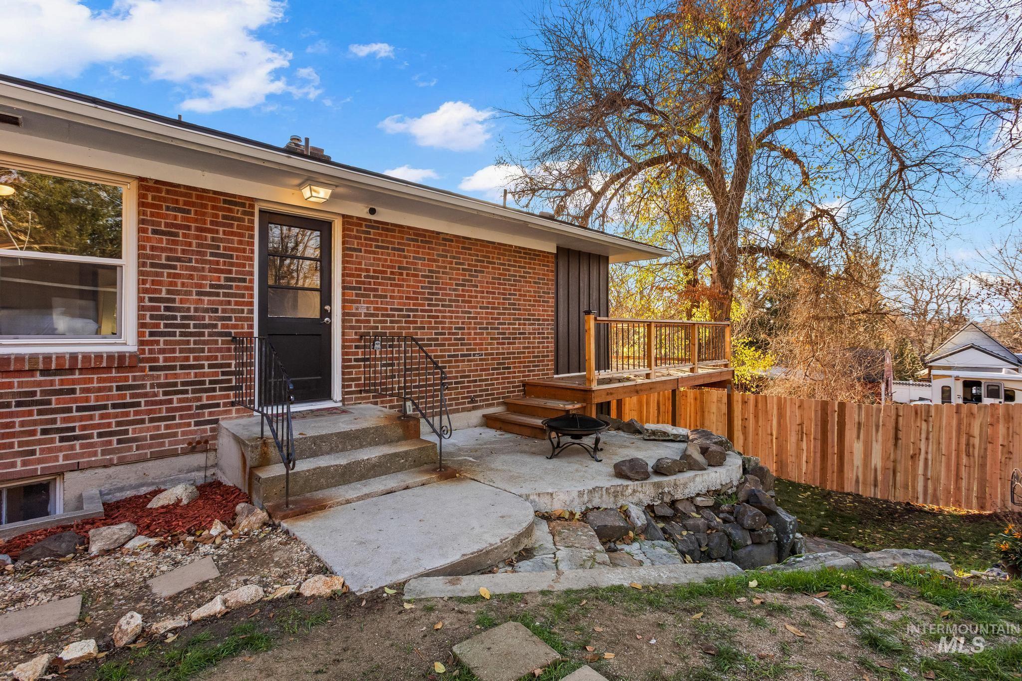 Doorway to property featuring brick siding and a wooden deck