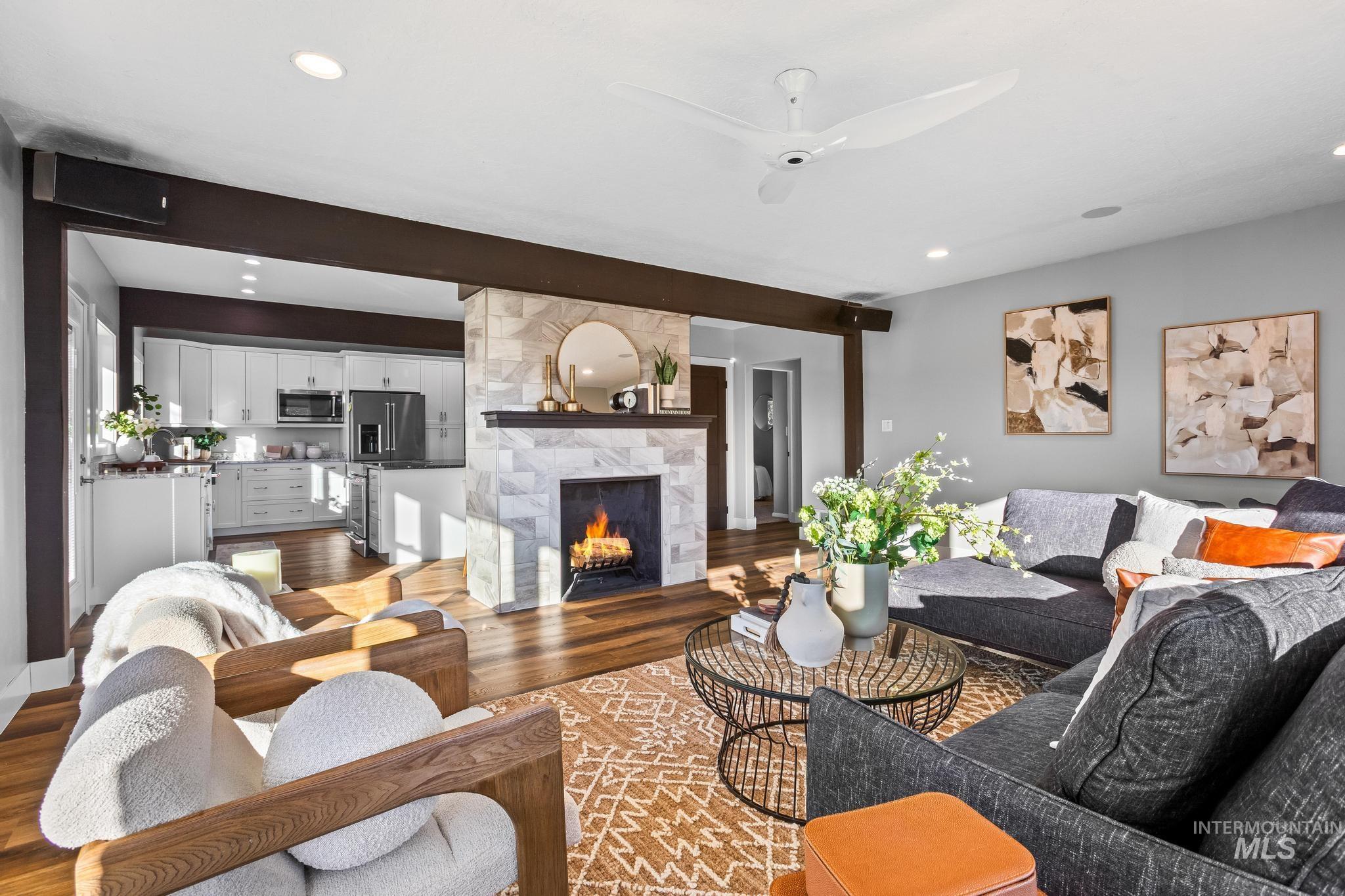 Living area featuring a large fireplace, wood finished floors, ceiling fan, and recessed lighting