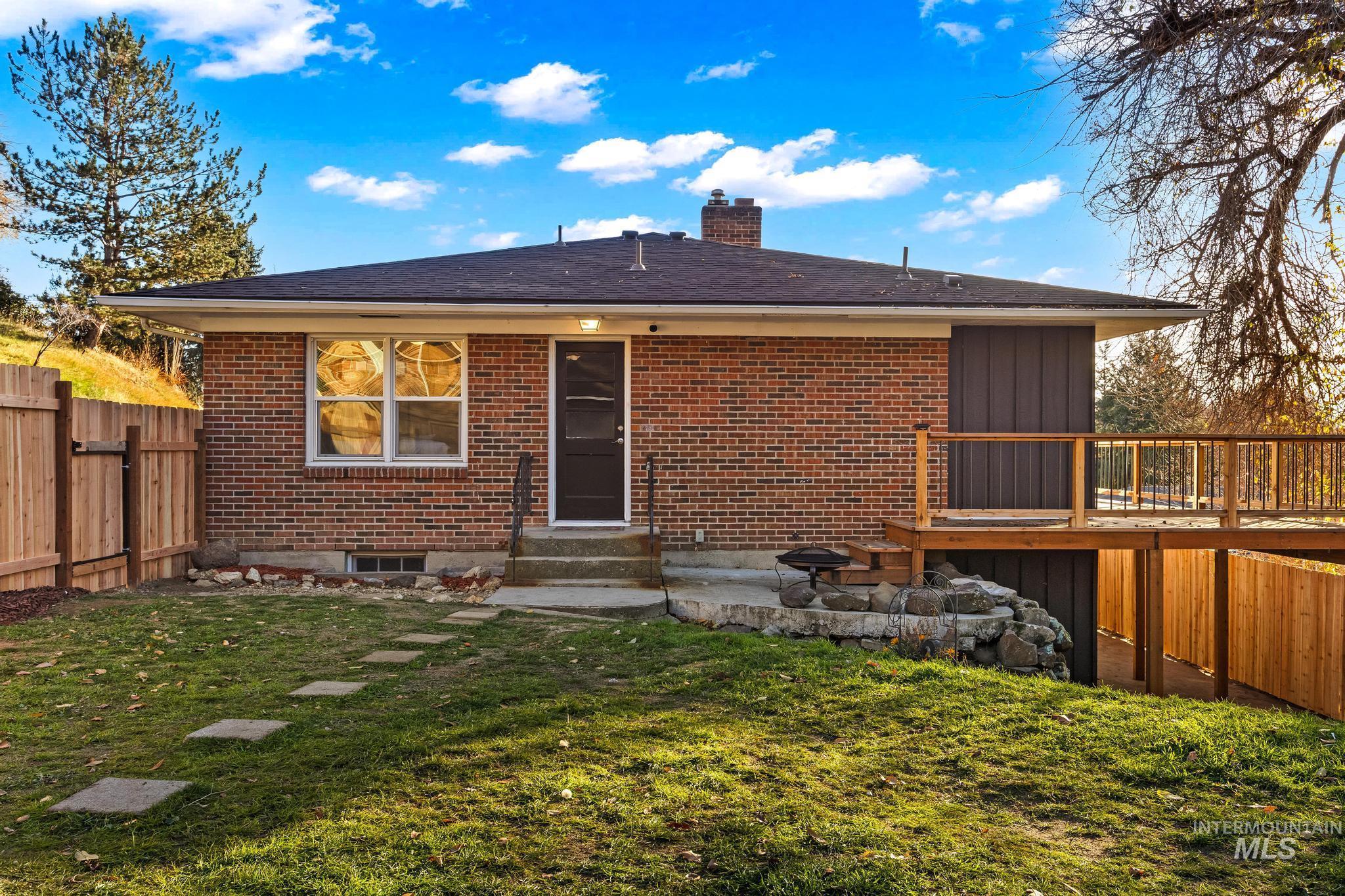 Back of house with brick siding, entry steps, a chimney, and roof with shingles