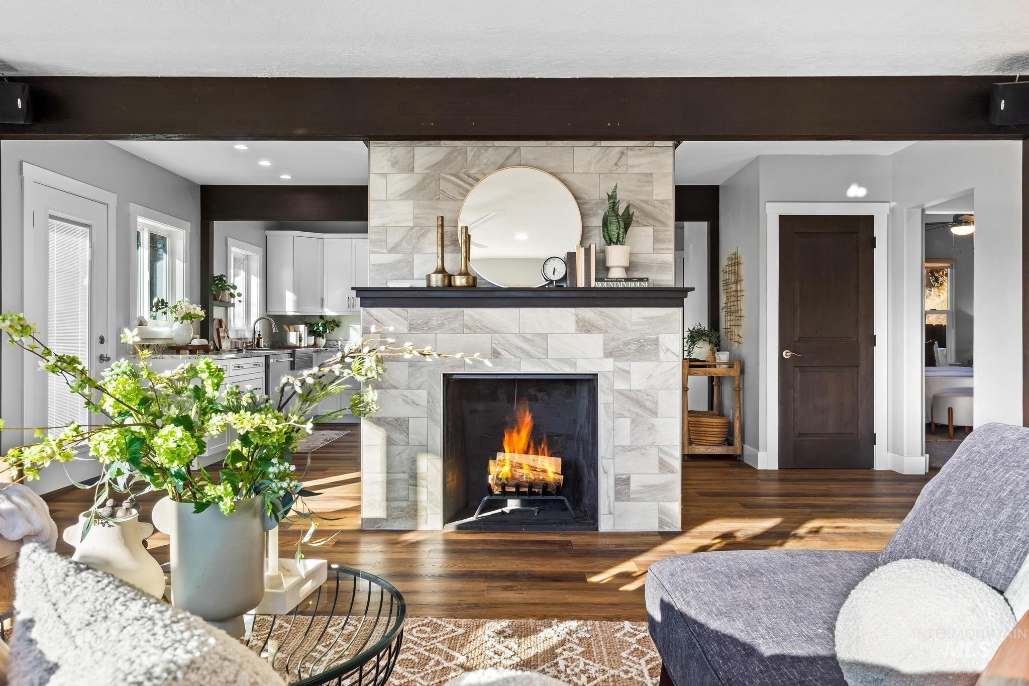 Living area featuring a fireplace, dark wood-style floors, and beamed ceiling