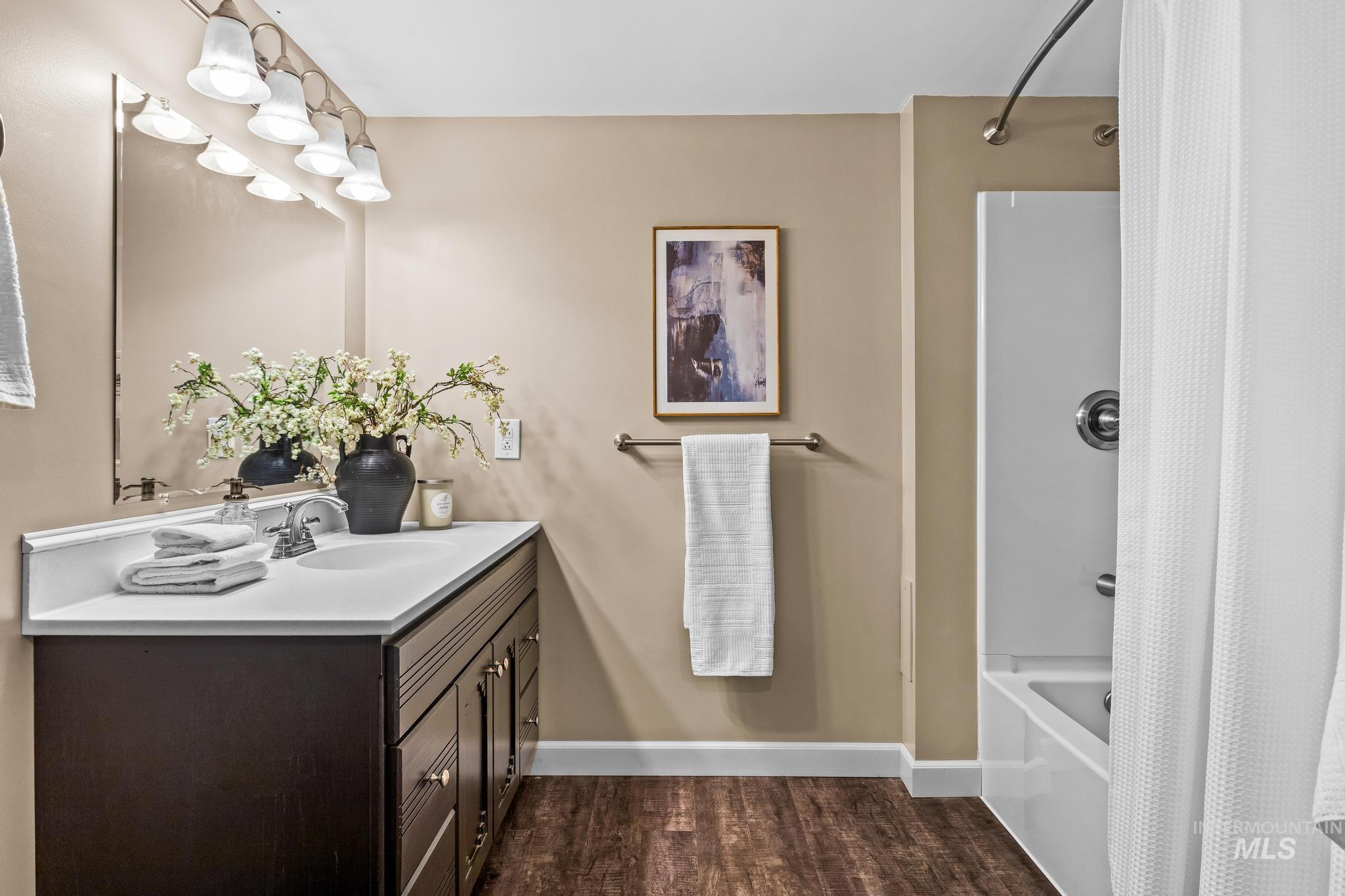 Bathroom with shower / tub combo, vanity, and dark wood-style flooring