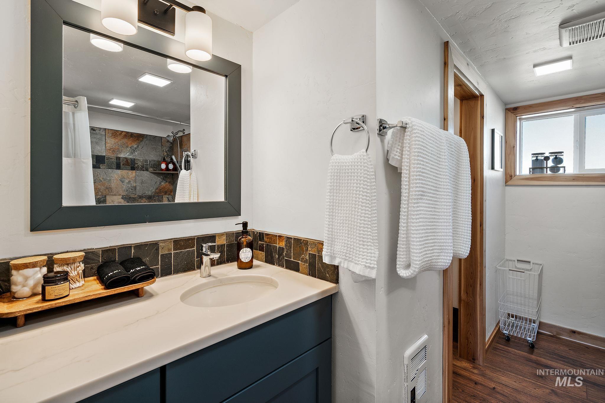 Bathroom featuring vanity, a shower with curtain, dark wood-style floors, and tasteful backsplash