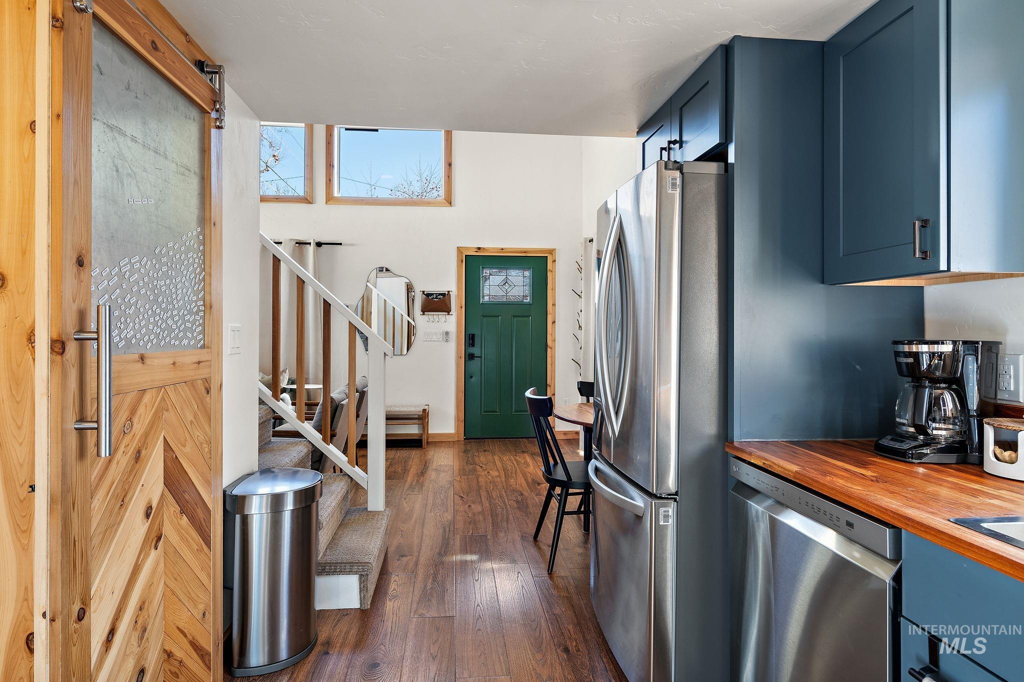 Kitchen featuring appliances with stainless steel finishes, dark wood-style flooring, blue cabinets, and wood counters