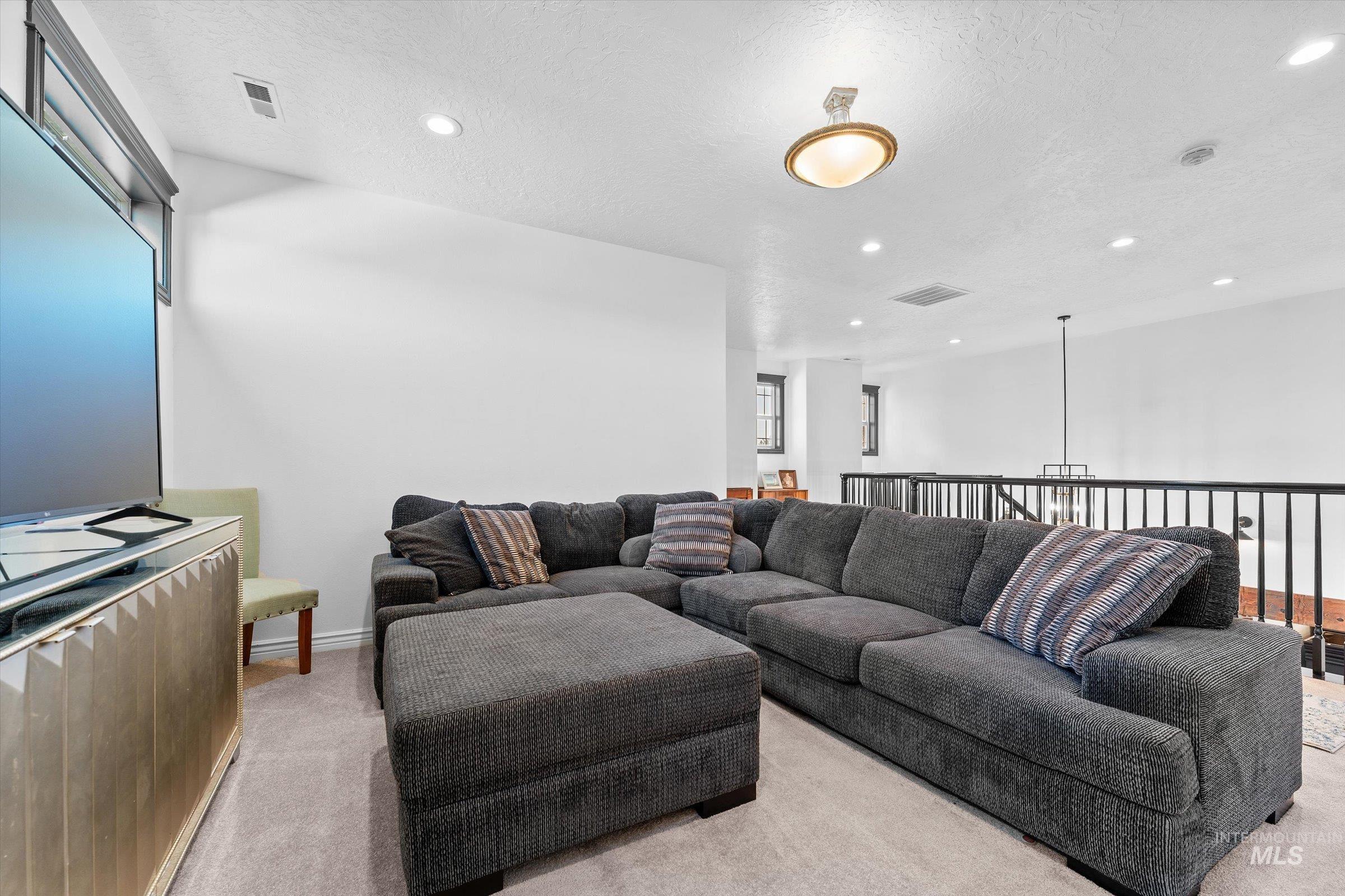 Carpeted living room featuring a textured ceiling and recessed lighting