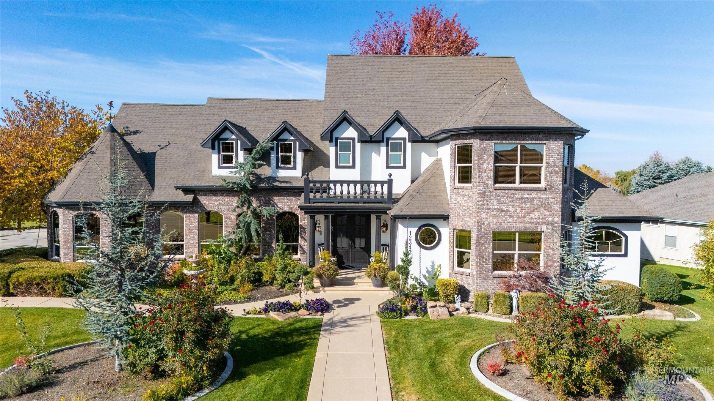 View of front of property featuring brick siding, a front lawn, a balcony, and roof with shingles