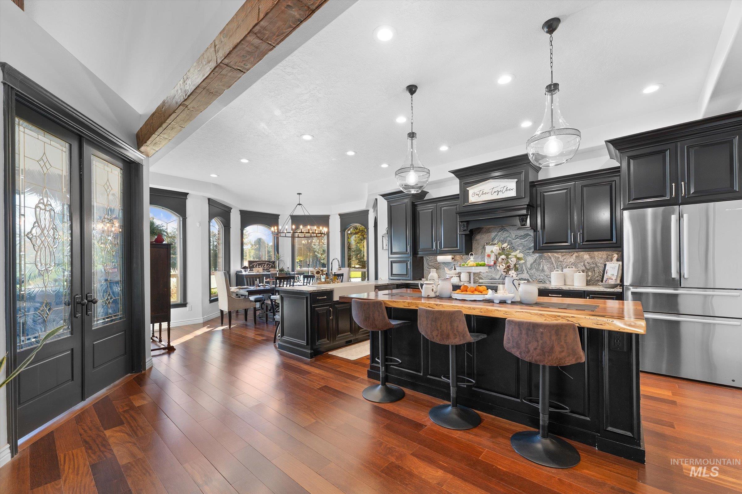 Kitchen featuring dark cabinetry, pendant lighting, freestanding refrigerator, recessed lighting, and decorative backsplash
