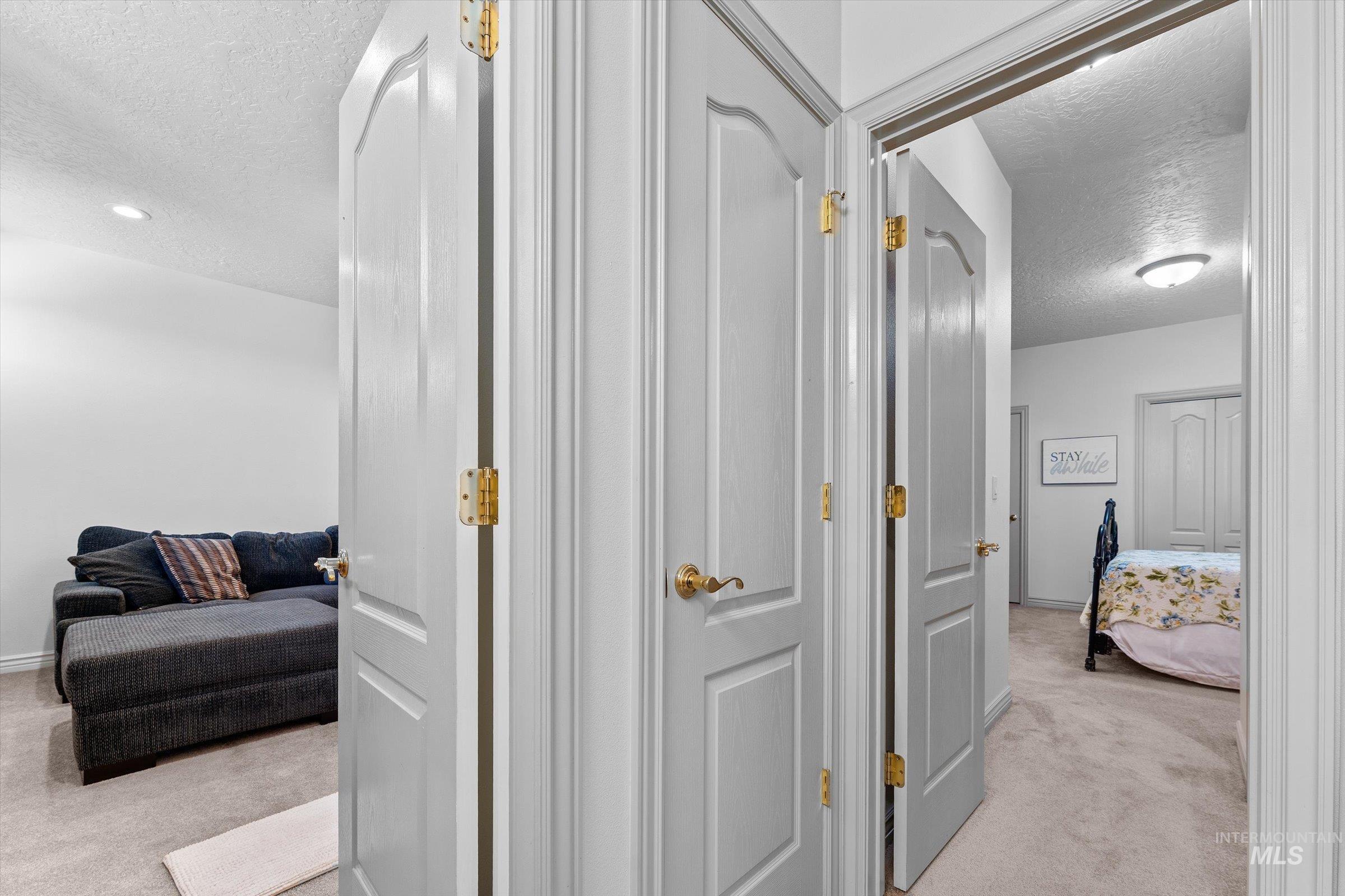 Hallway with a textured ceiling and light carpet