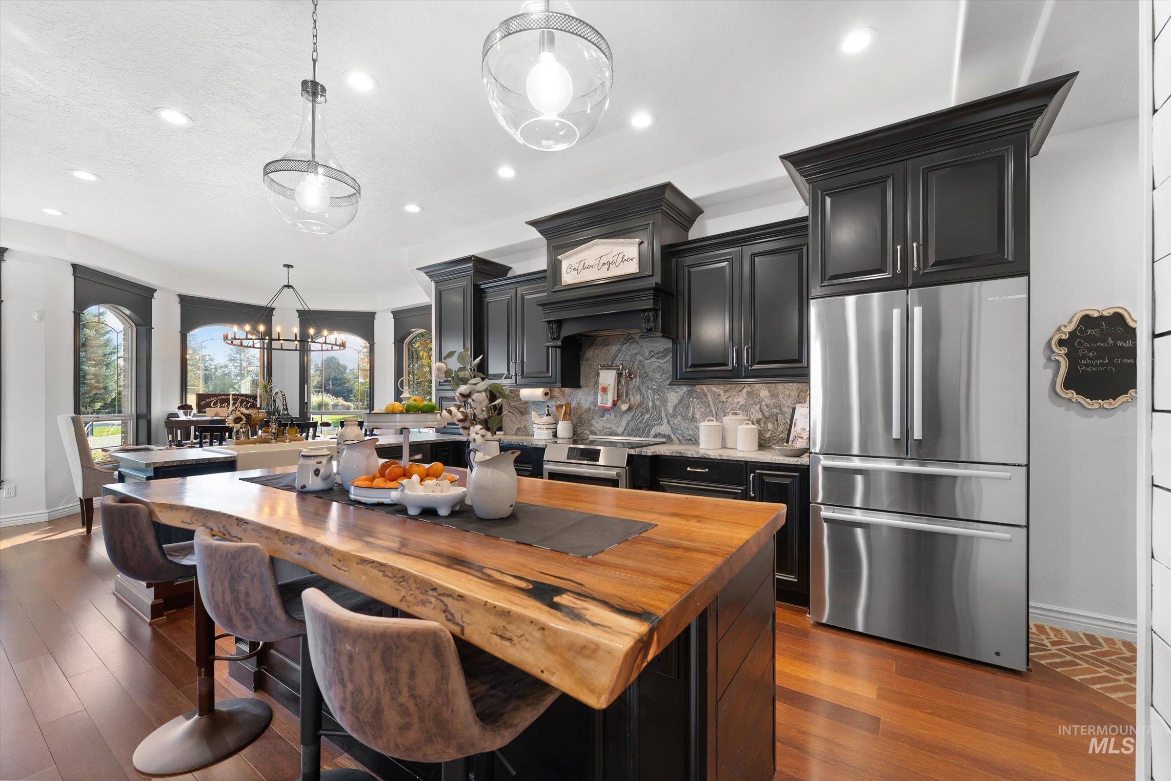 Kitchen with dark cabinets, wooden counters, stainless steel appliances, a breakfast bar, and recessed lighting