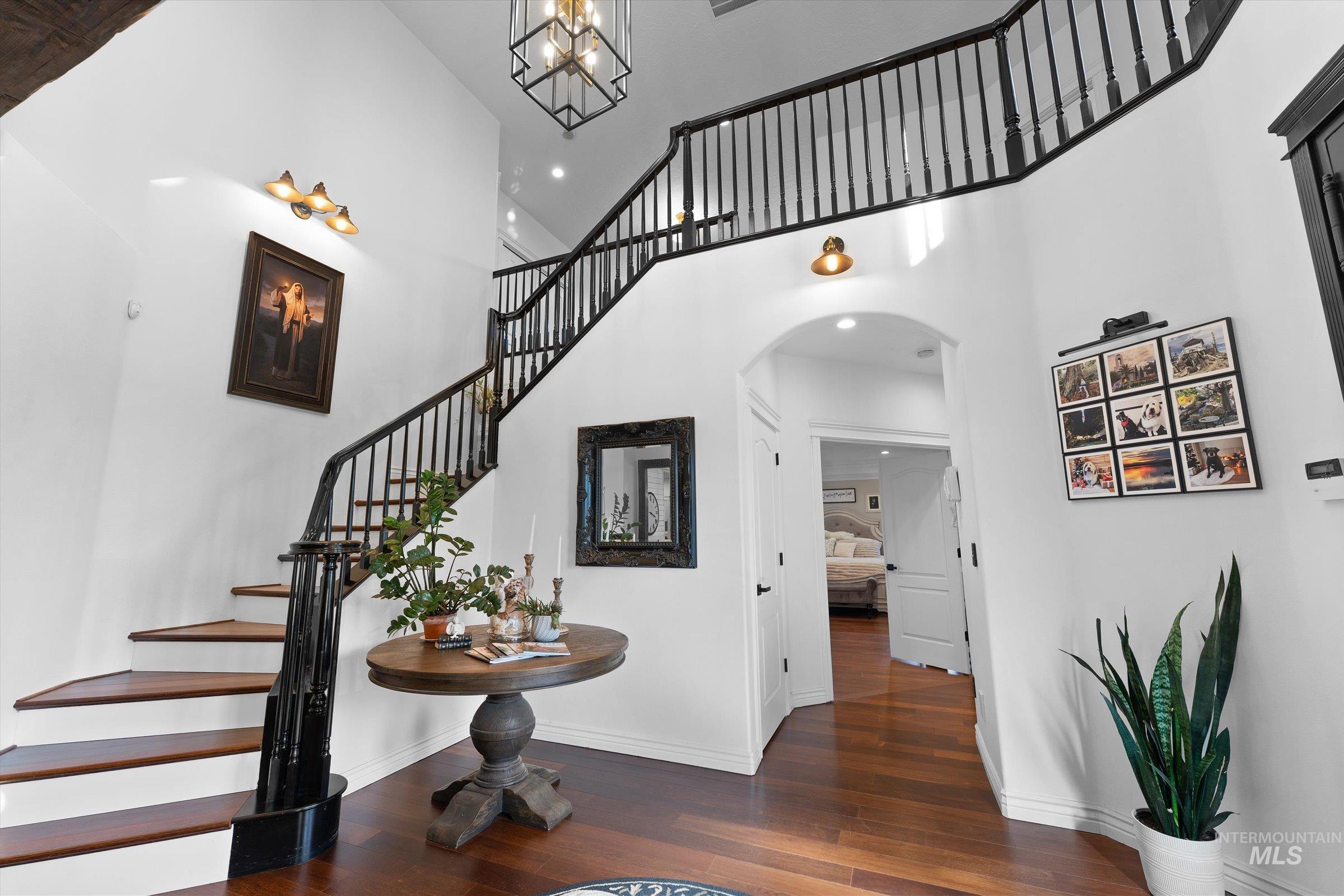 Entrance foyer featuring stairs, dark wood-type flooring, a towering ceiling, arched walkways, and recessed lighting