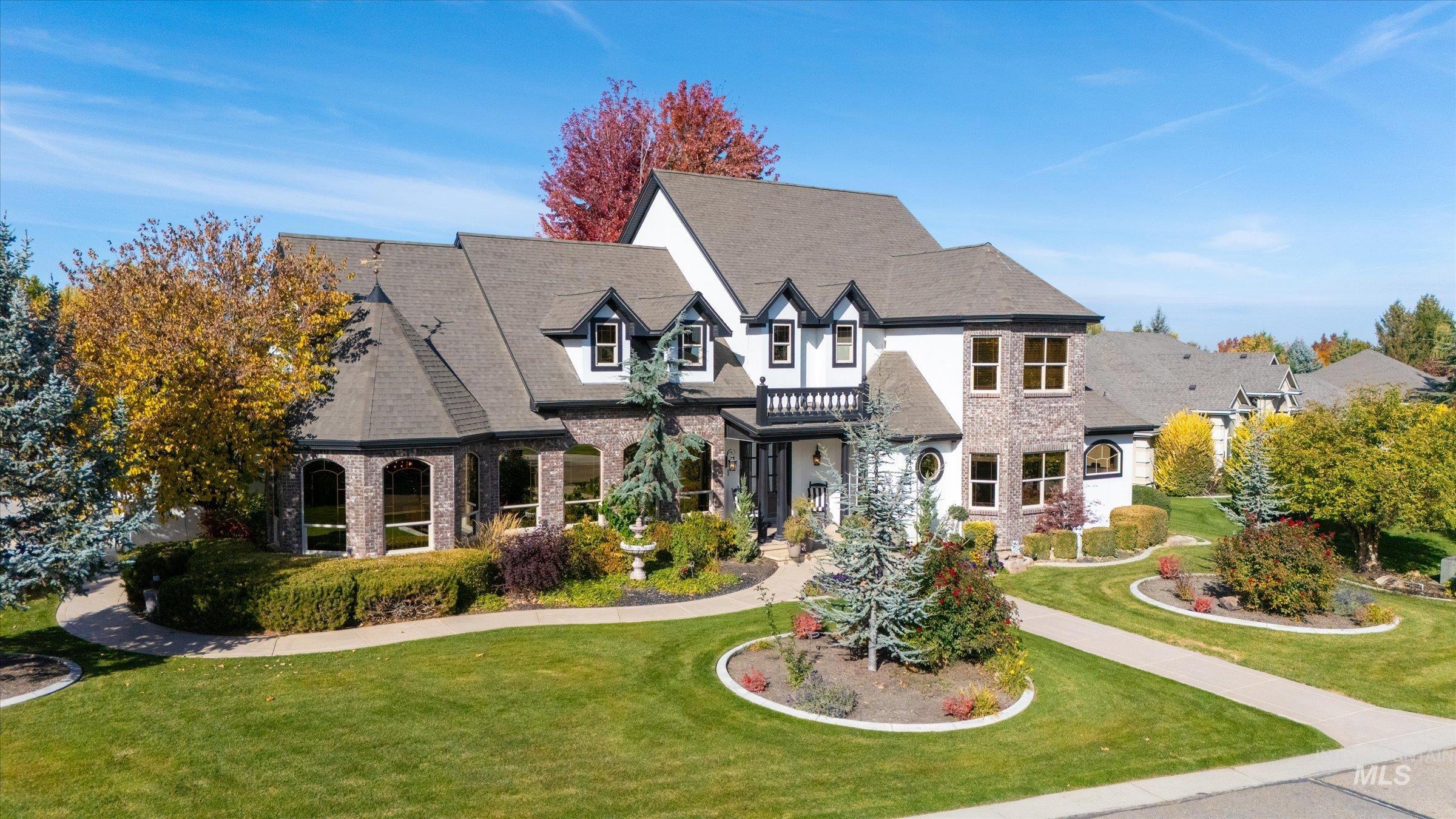 French country style house featuring a front yard, a balcony, and brick siding