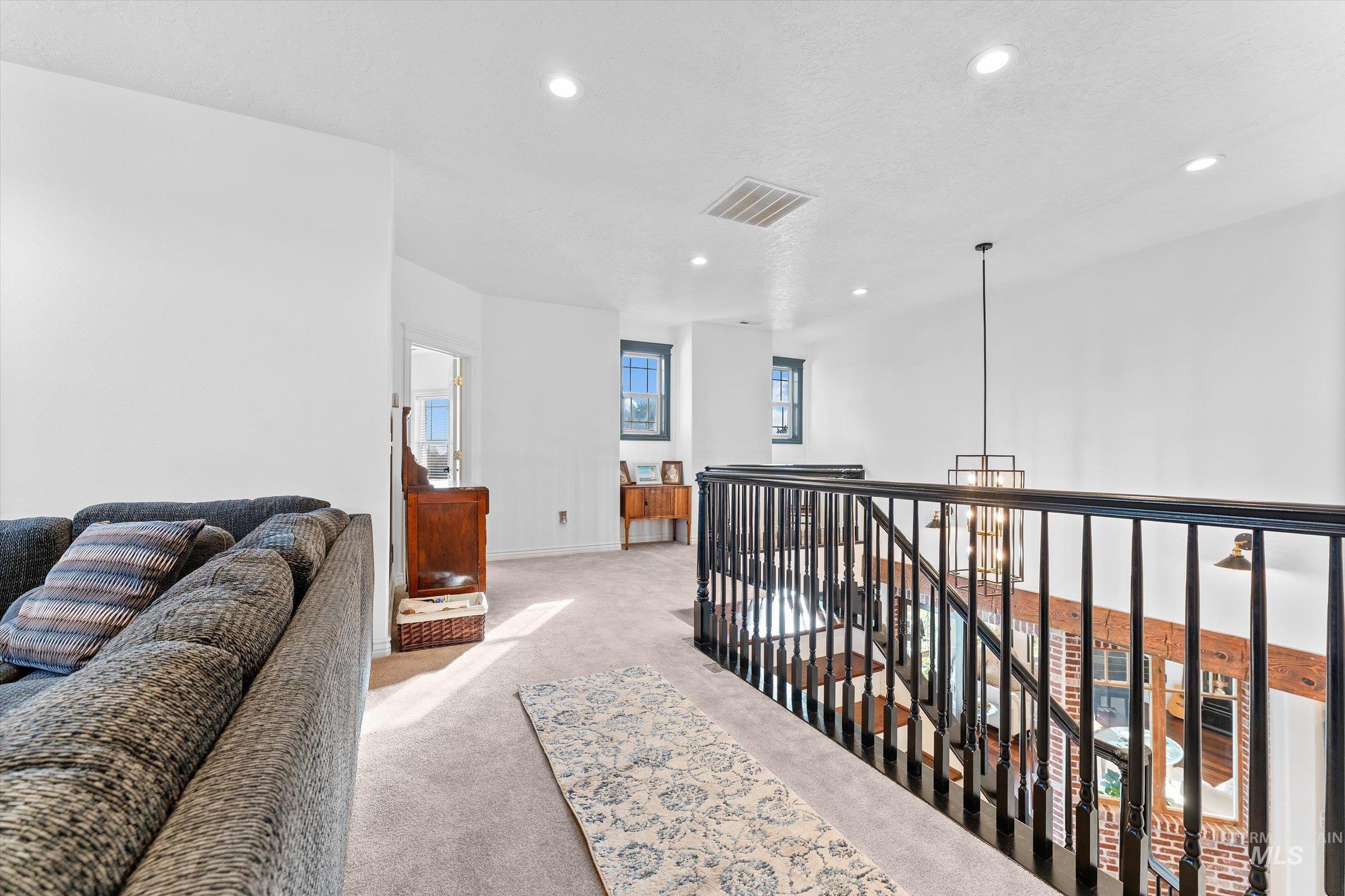 Hall featuring light colored carpet, recessed lighting, a textured ceiling, and an upstairs landing
