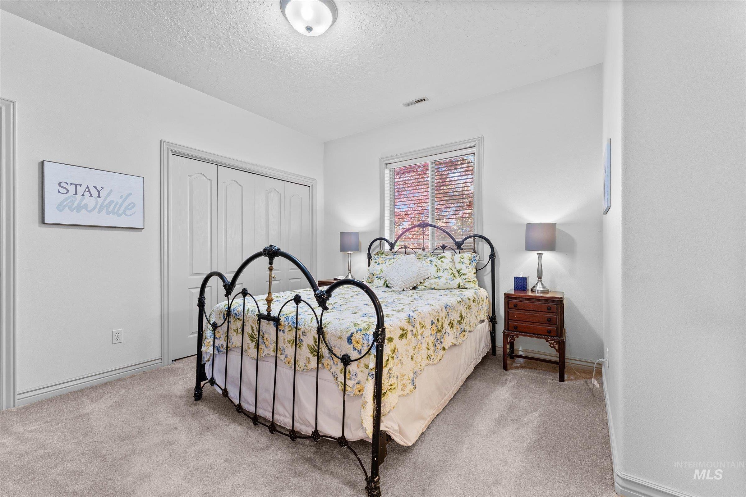 Bedroom featuring light colored carpet, a textured ceiling, and a closet