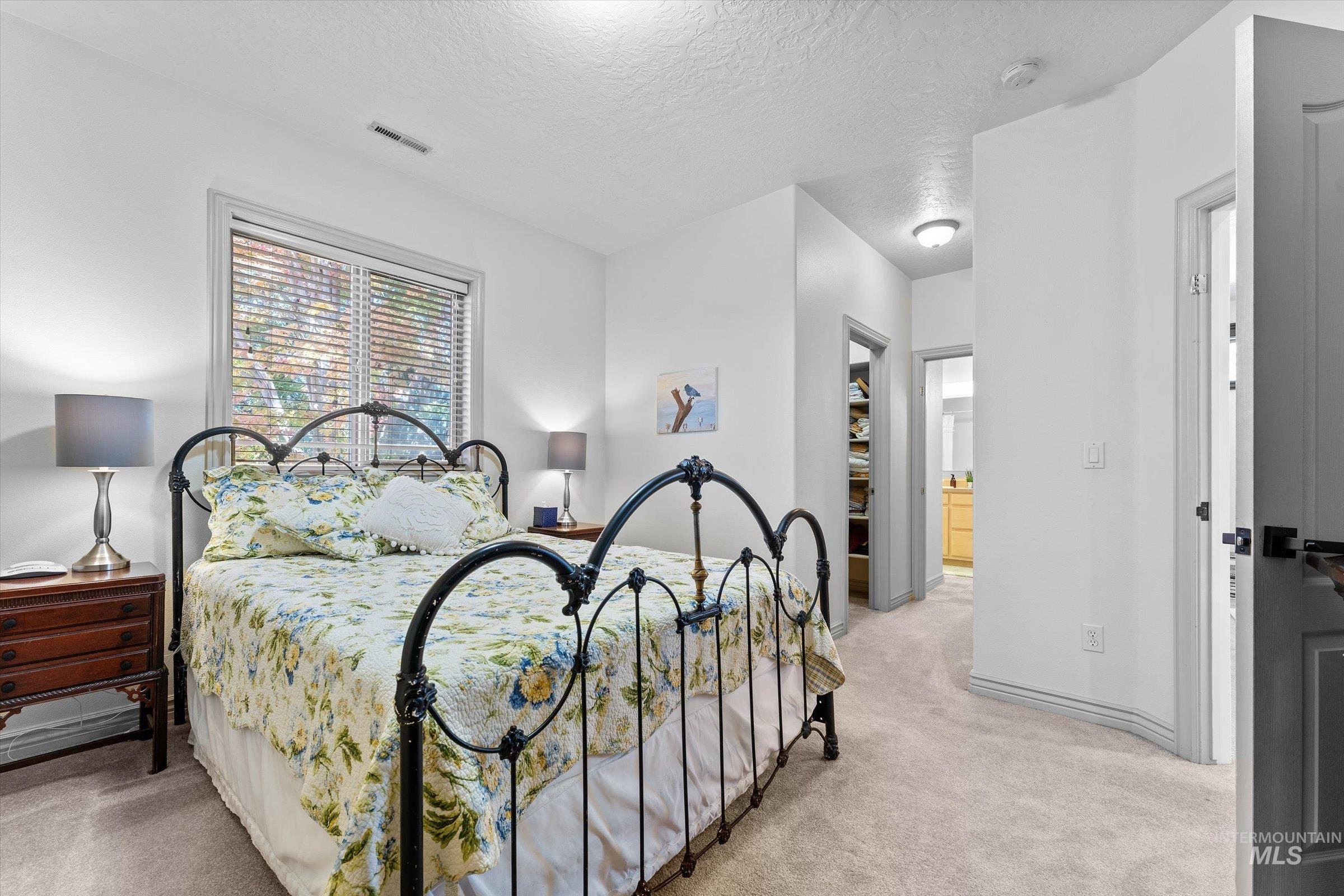 Bedroom featuring light colored carpet, a textured ceiling, a closet, and connected bathroom