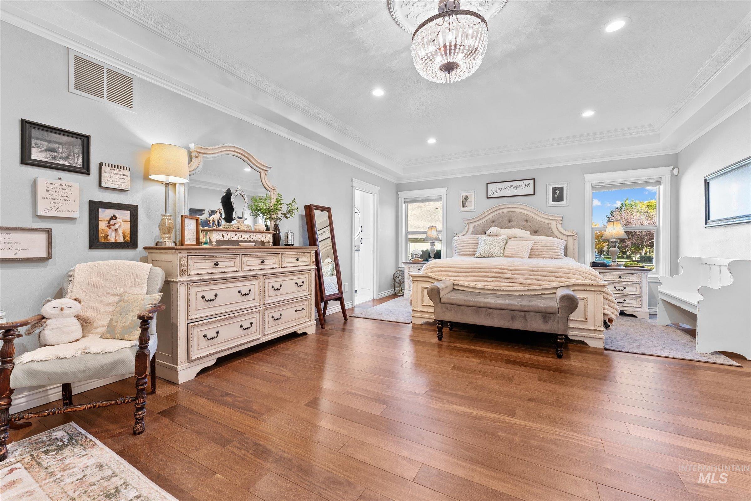 Bedroom featuring dark wood-type flooring, crown molding, recessed lighting, and a chandelier
