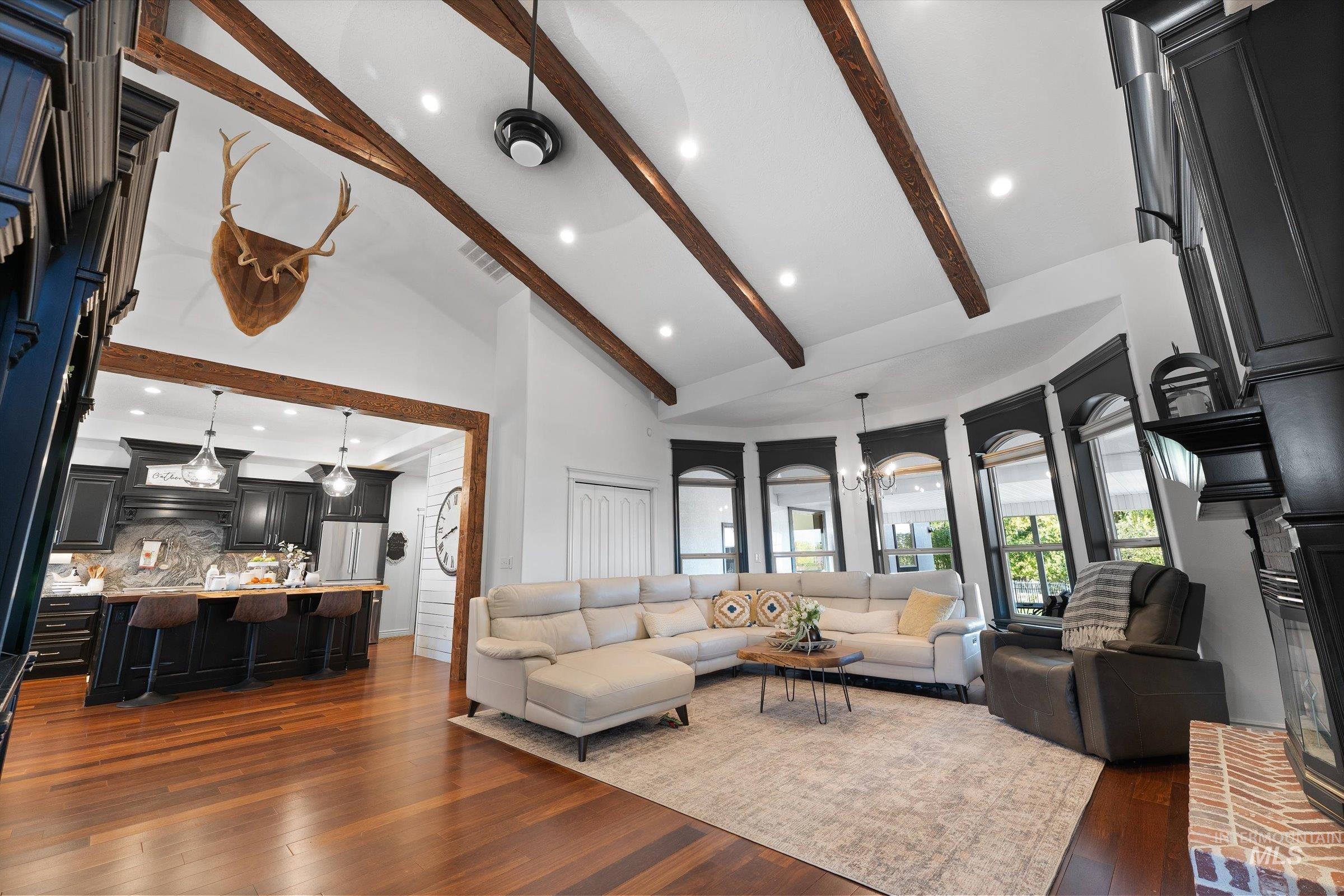 Living room featuring high vaulted ceiling, a chandelier, dark wood-type flooring, beam ceiling, and recessed lighting