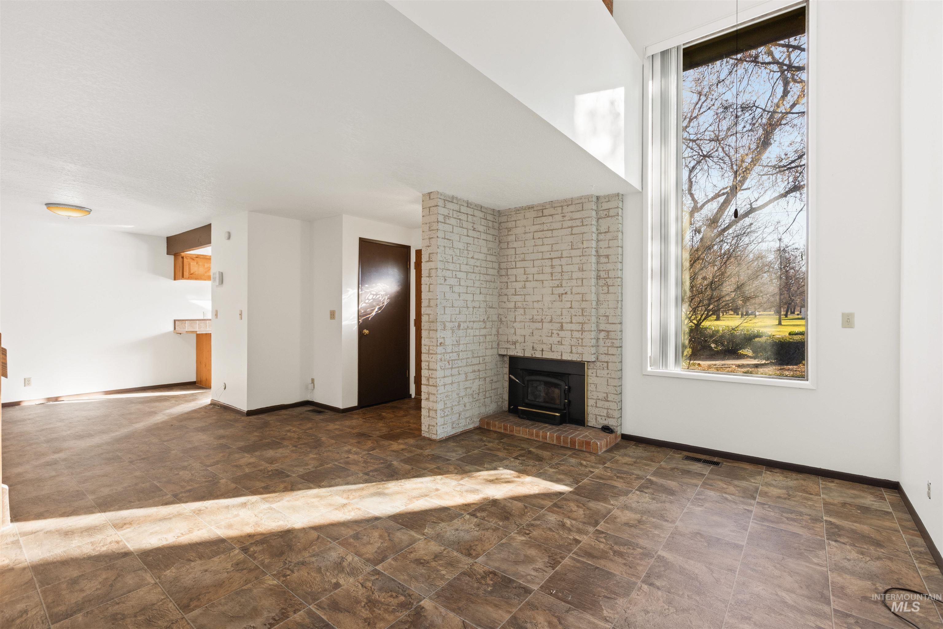 Unfurnished living room featuring stone finish flooring and a wood stove