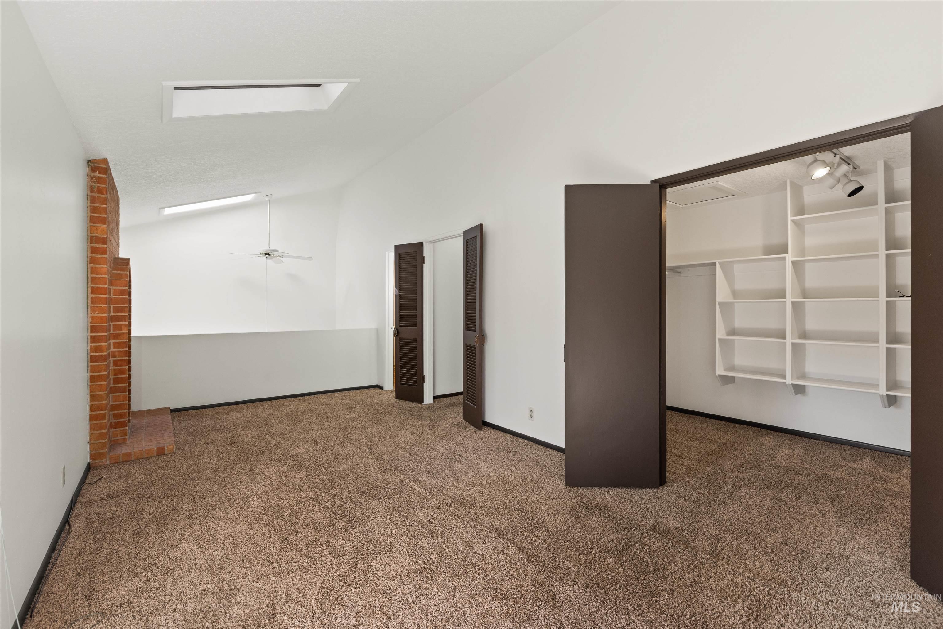 Unfurnished bedroom with carpet flooring and high vaulted ceiling