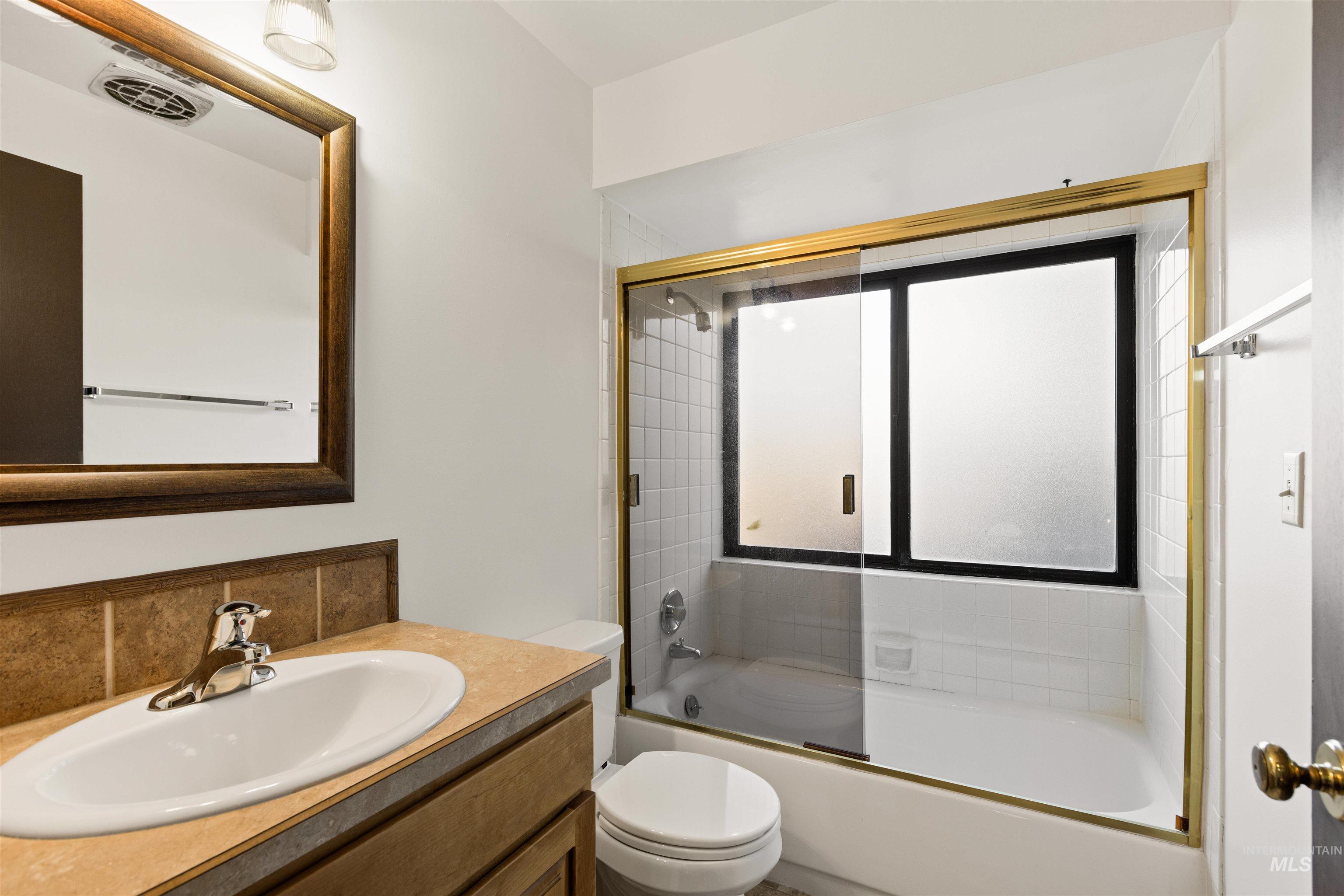 Bathroom featuring vanity and enclosed tub / shower combo