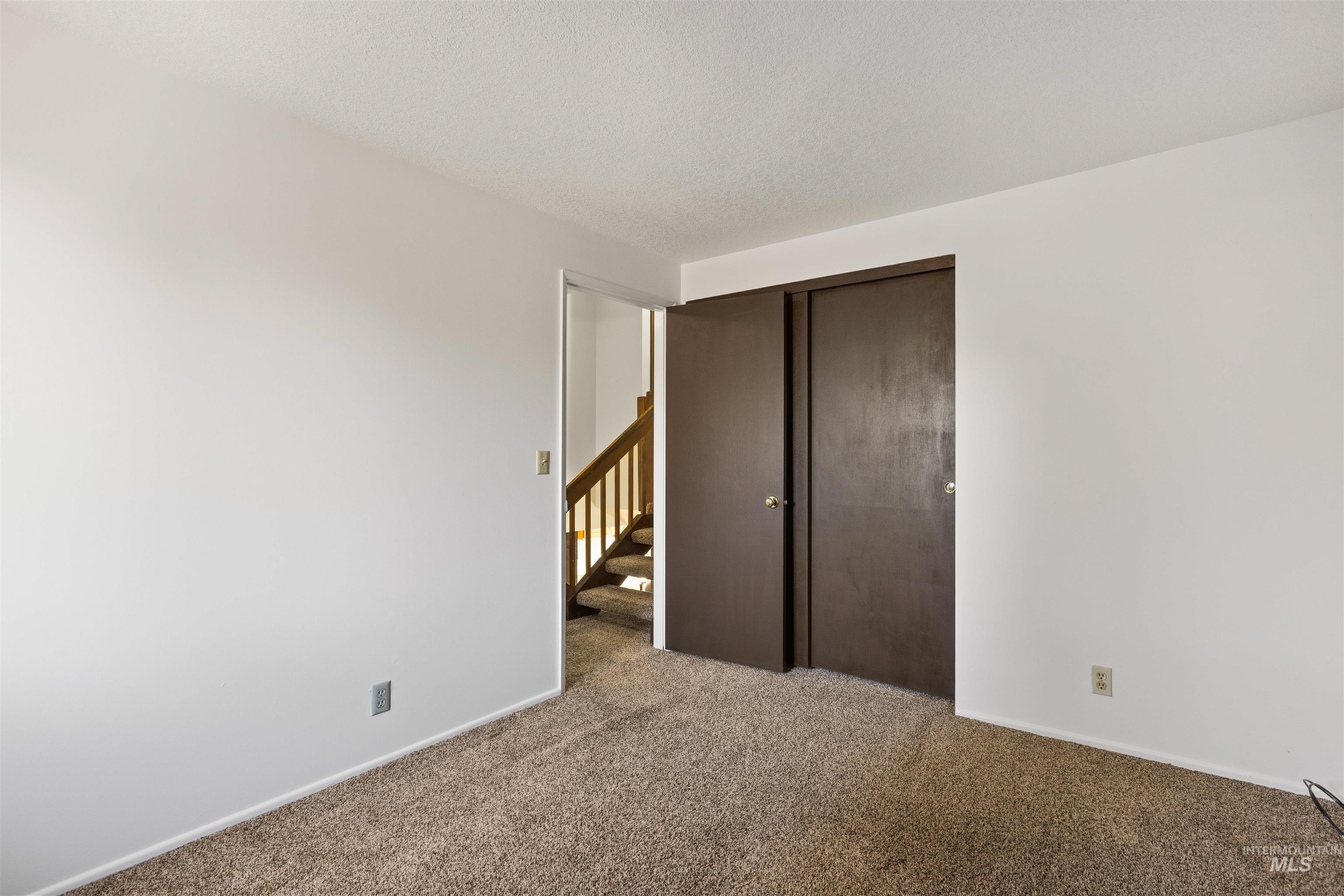 Unfurnished bedroom featuring a closet, carpet flooring, and a textured ceiling